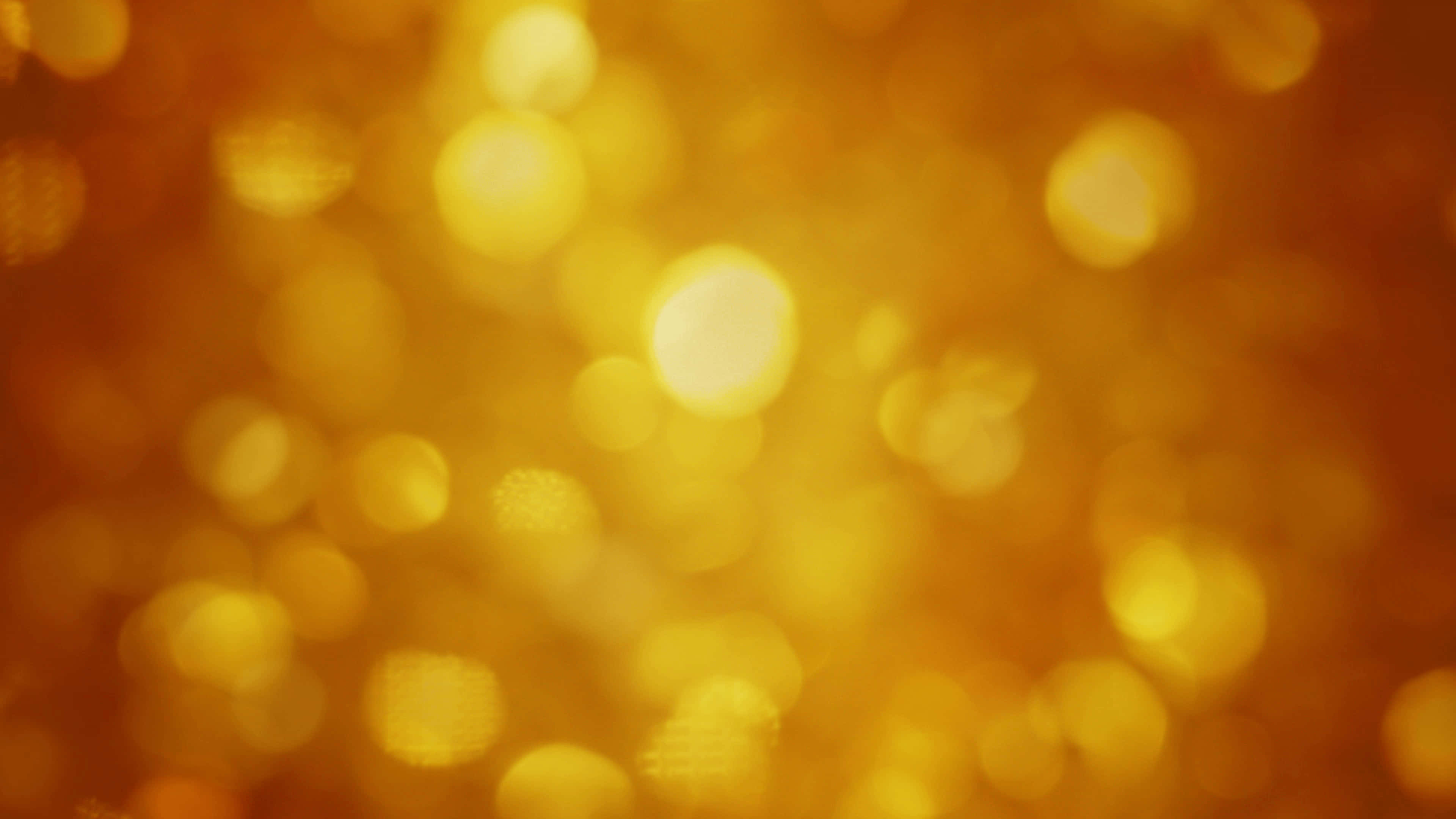 Yellow Glitter 桌布 壁紙 — 溫暖的金色散景背景，帶有柔和發光的圓圈，營造出夢幻而燦爛的氛圍。