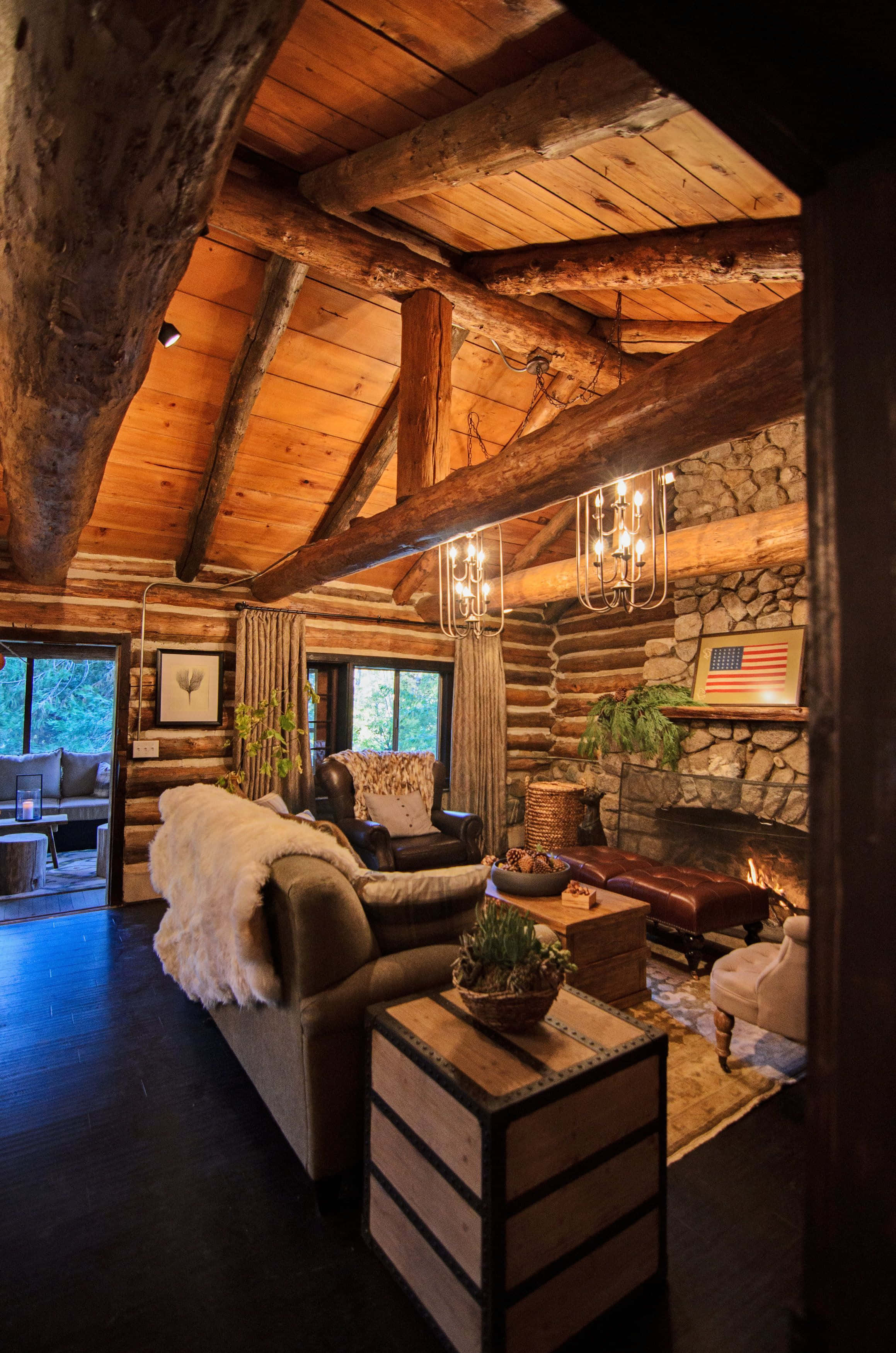 Log Cabin 桌布 壁紙 — 溫暖質樸的木屋客廳，配有石頭壁爐、發光的餘燼、木樑和舒適的皮革家具。