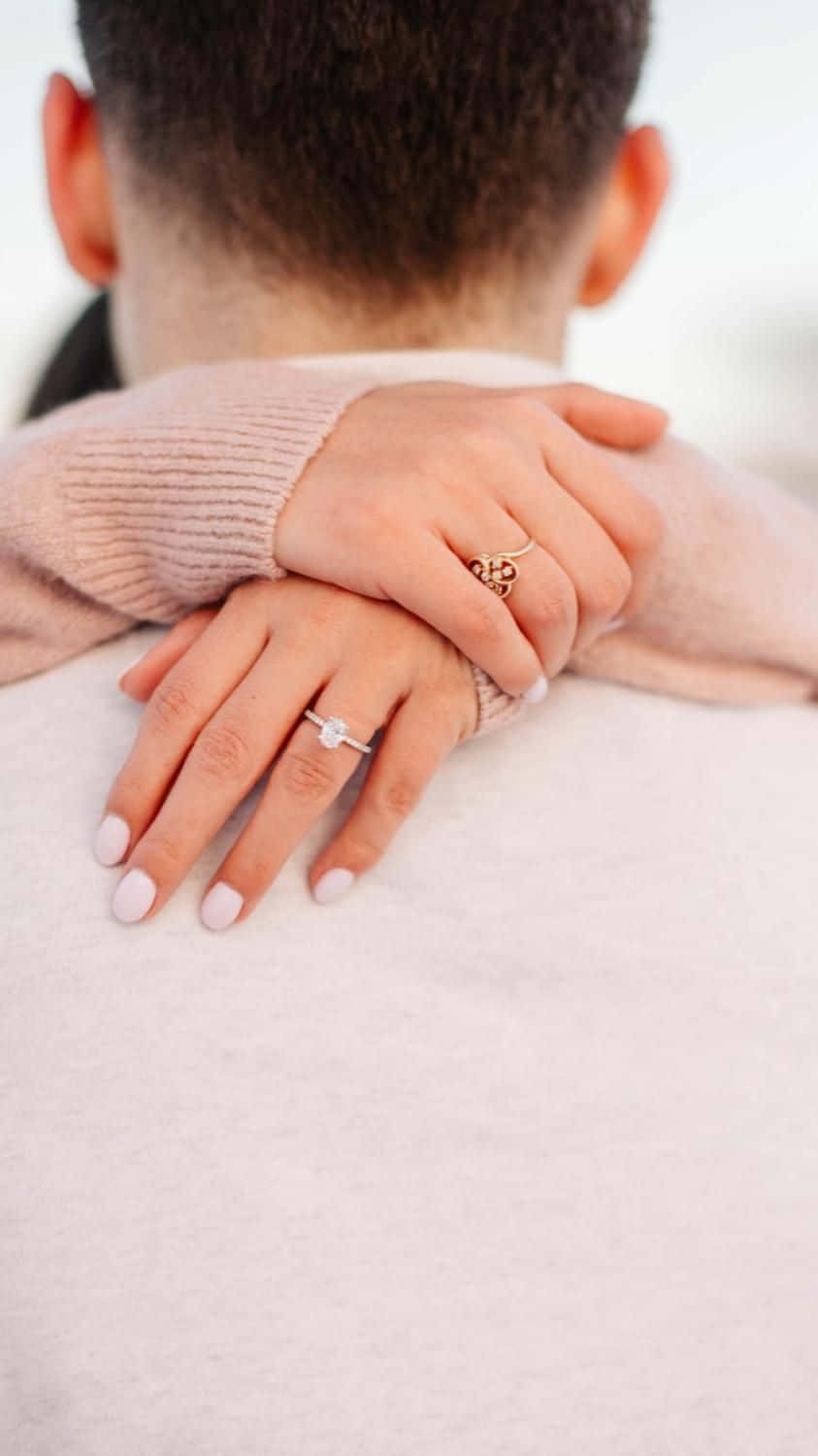 engagement 桌布 壁紙 — 溫柔的時刻，女人的手放在男人的肩膀上，兩人都戴著結婚戒指，柔和粉彩的色調。