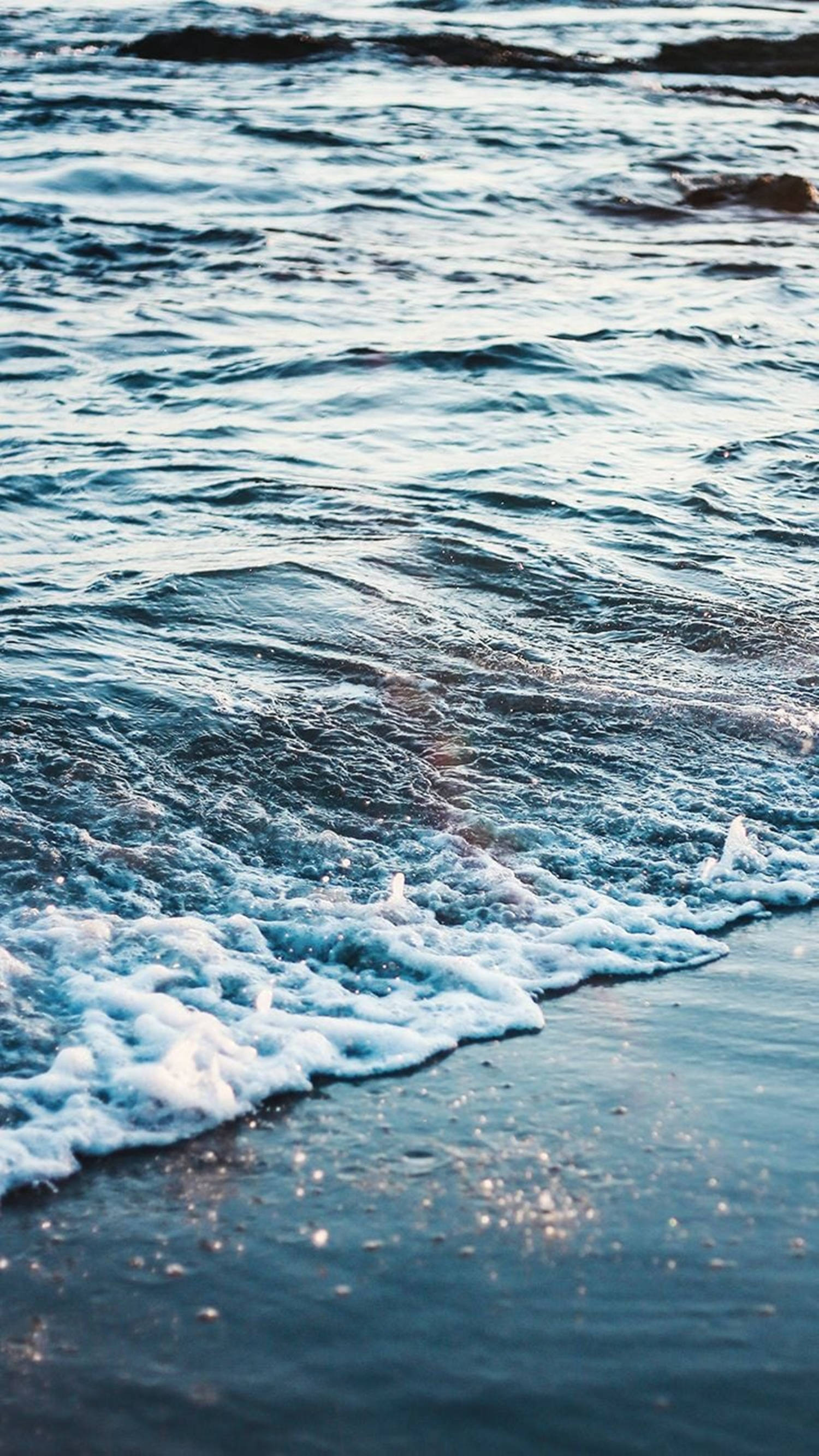 海洋 桌布 壁紙 — 溫柔的海浪帶著白色泡沫在柔和的金色光線下滾上黑暗的沙灘。