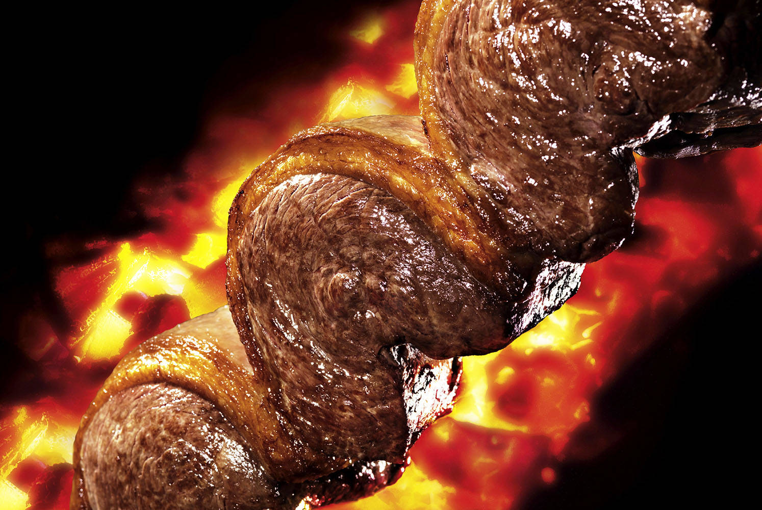 meat 桌布 壁紙 — 滋滋作響的串燒肉在鮮豔的火焰上旋轉，特寫鏡頭中帶有發光的餘燼和燒焦的外皮。