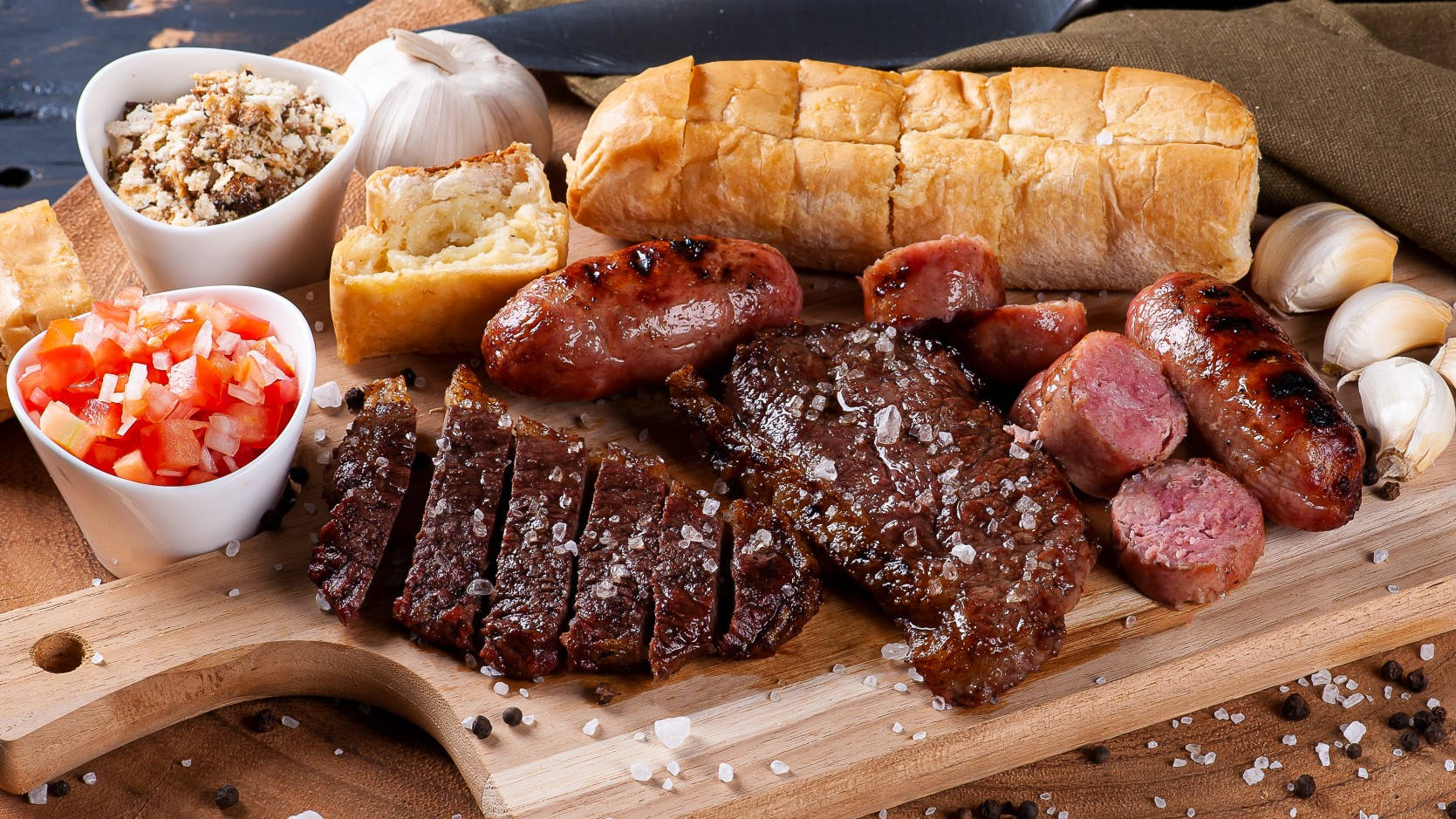 meat 桌布 壁紙 — 滋滋作響的烤牛排香腸和麵包放在木板上，搭配新鮮番茄醬和蒜瓣。