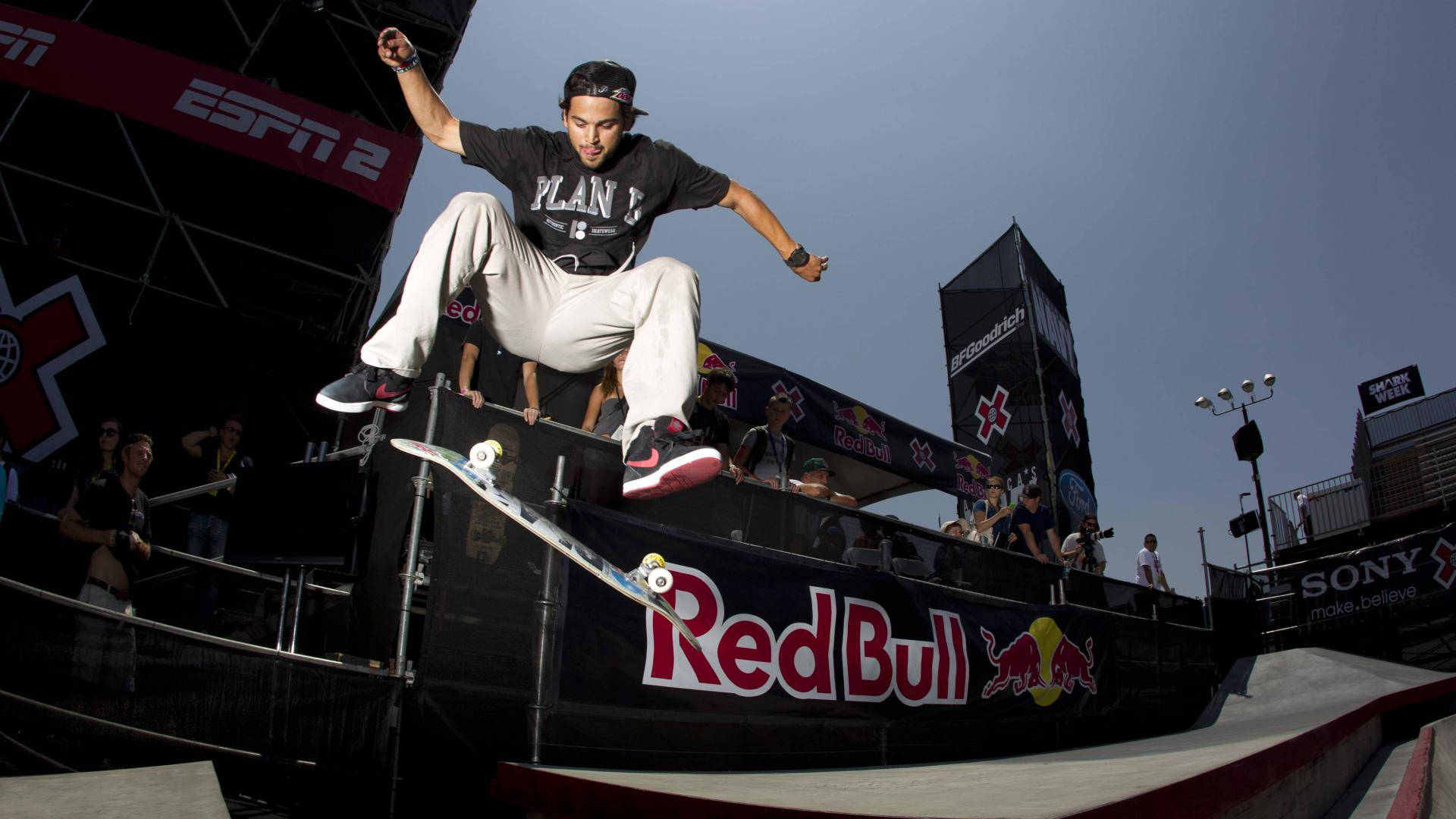 Skater Boy 桌布 壁紙 — 滑板手在半空中越過Red Bull品牌坡道表演技巧，在陽光明媚的戶外活動中。