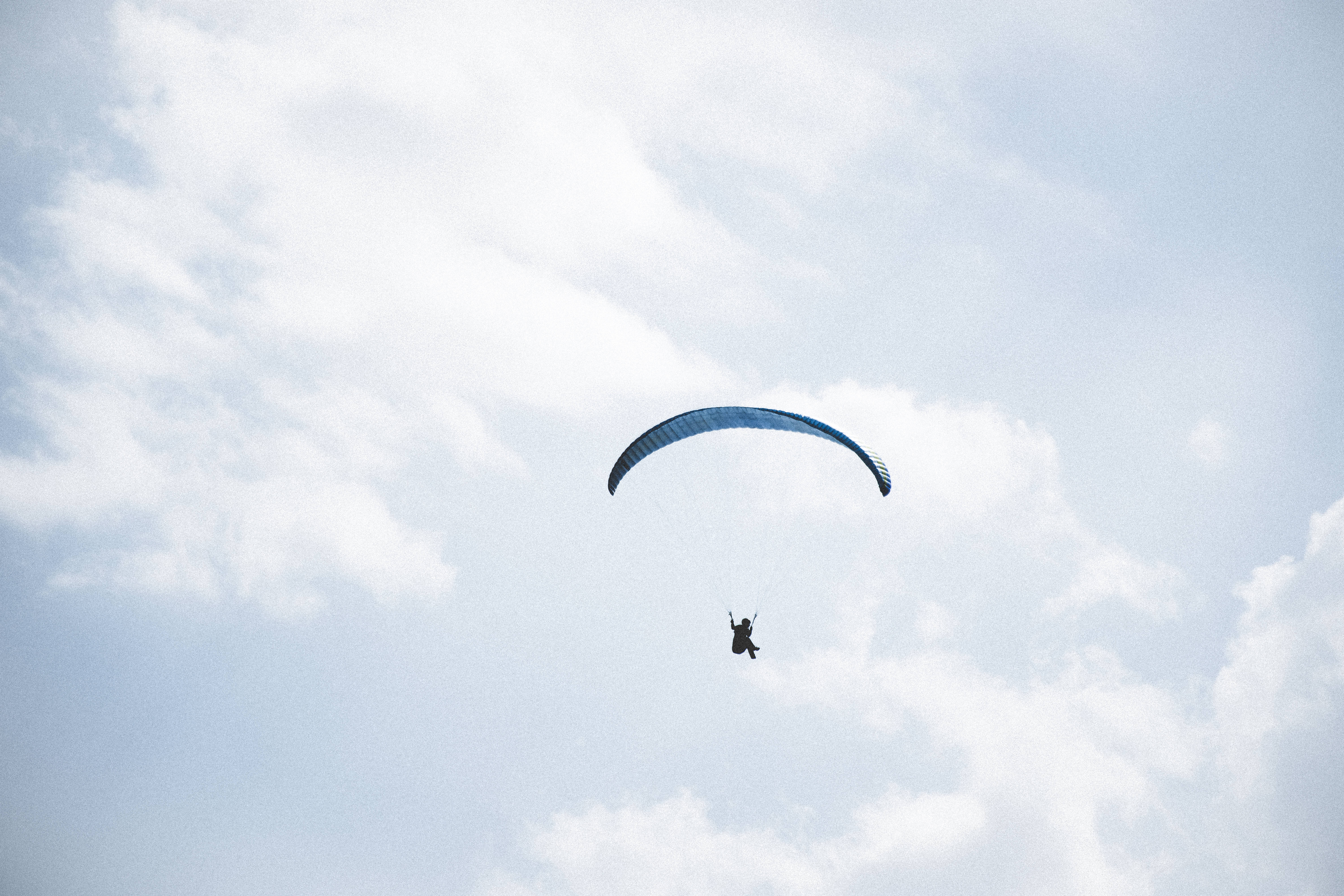 Paragliding 桌布 壁紙 — 滑翔傘在佈滿柔和白雲的明亮天空中優雅地翱翔。