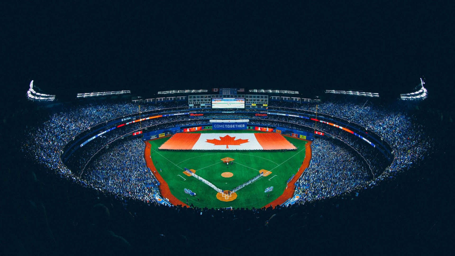Baseball Stadium 桌布 壁紙 — 滿座棒球場的夜間鳥瞰圖，場地上有一面巨大的加拿大國旗，藍色燈光照亮人群。