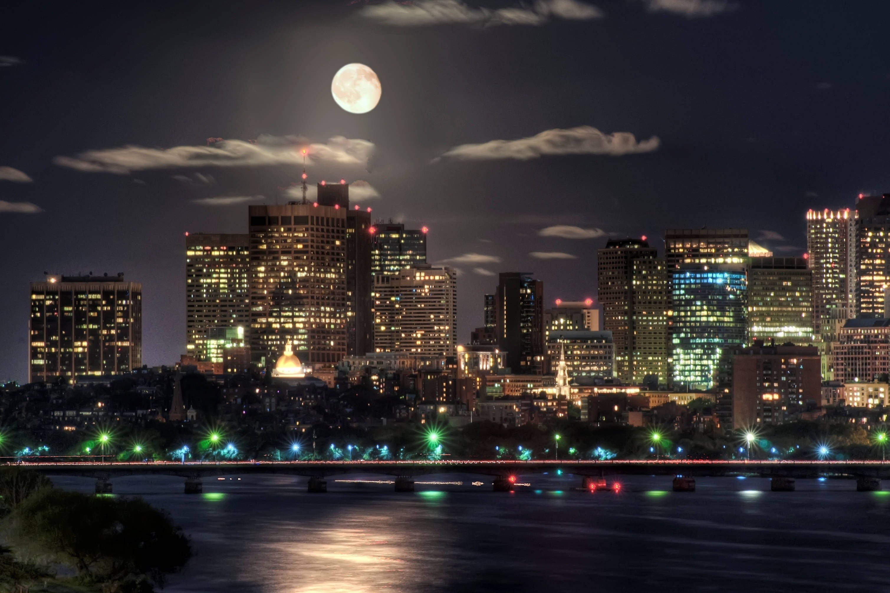 夜晚 桌布 壁紙 — 滿月在夜間照亮充滿活力的城市天際線，燈光倒映在下面的河流中。