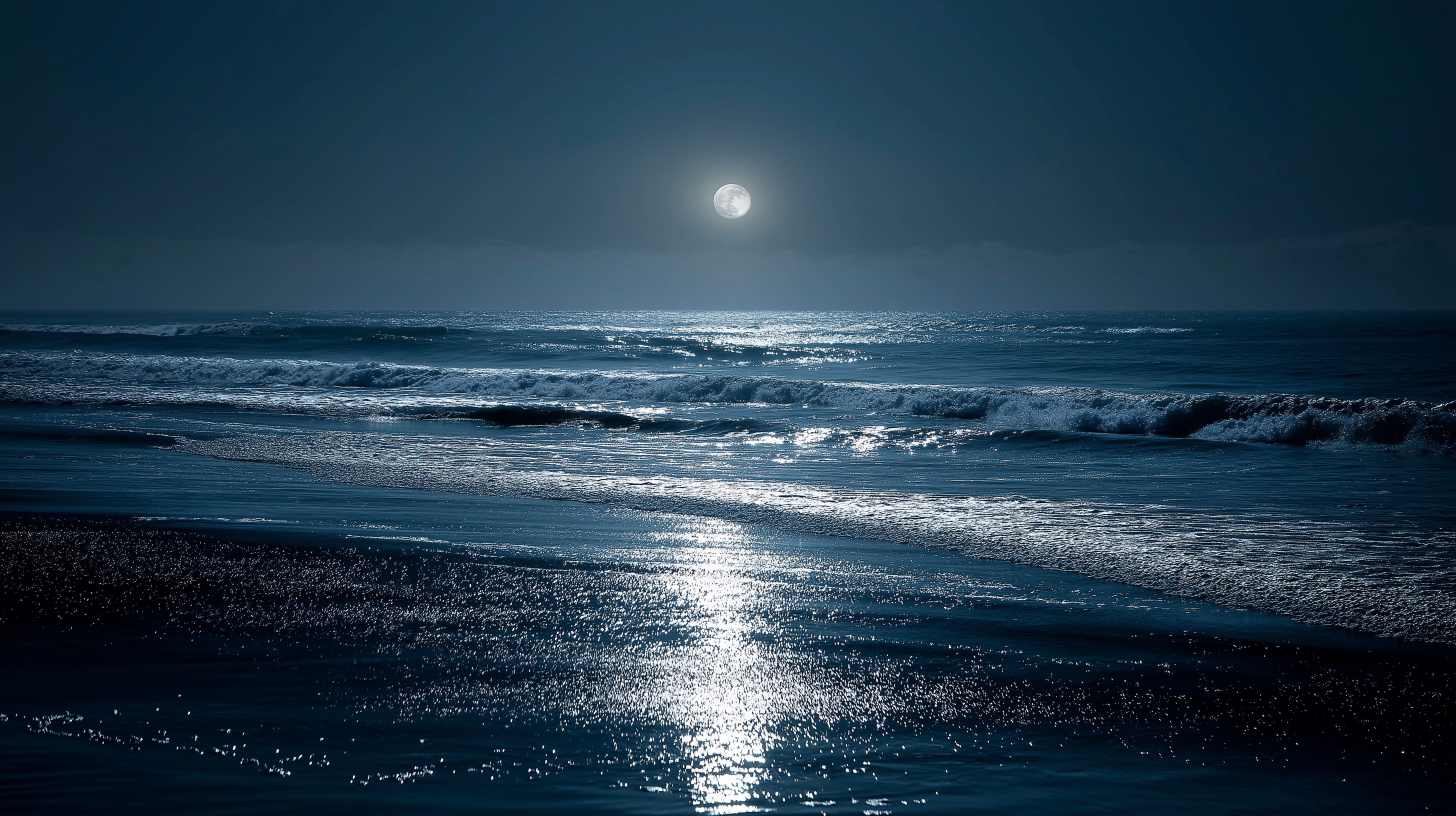 full moon 桌布 壁紙 — 滿月在深藍色夜空下，在滾上濕沙灘的黑暗海浪上投射出一條閃爍的路徑。