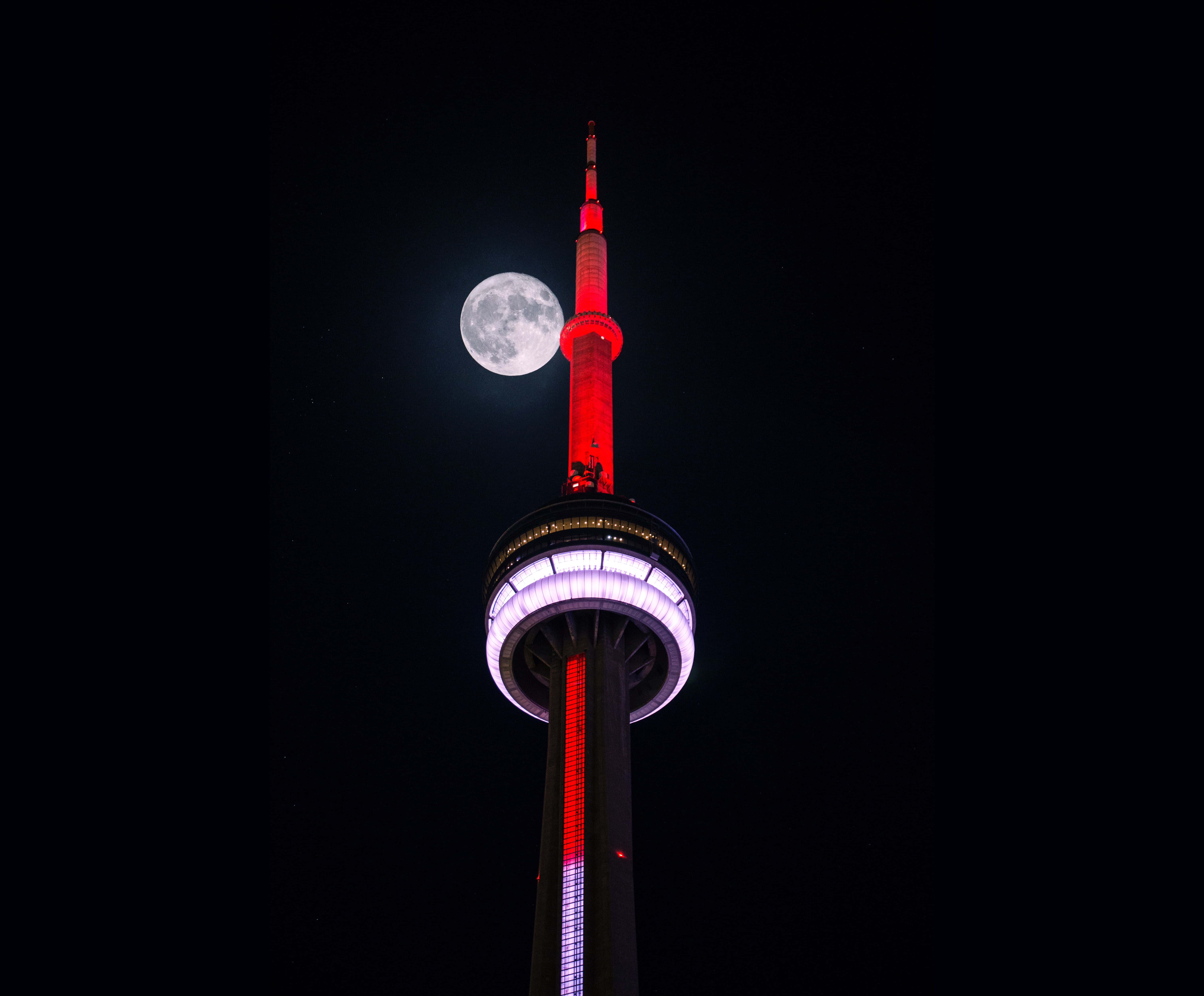 月光 桌布 壁紙 — 滿月在照亮的CN塔旁邊，在深黑色夜空下發光。