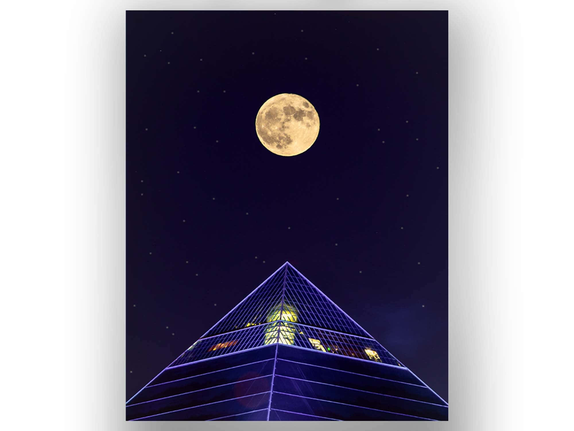 Moon Aesthetic 桌布 壁紙 — 滿月在繁星點點的夜空下，在發光的藍色金字塔形建築上方閃耀。
