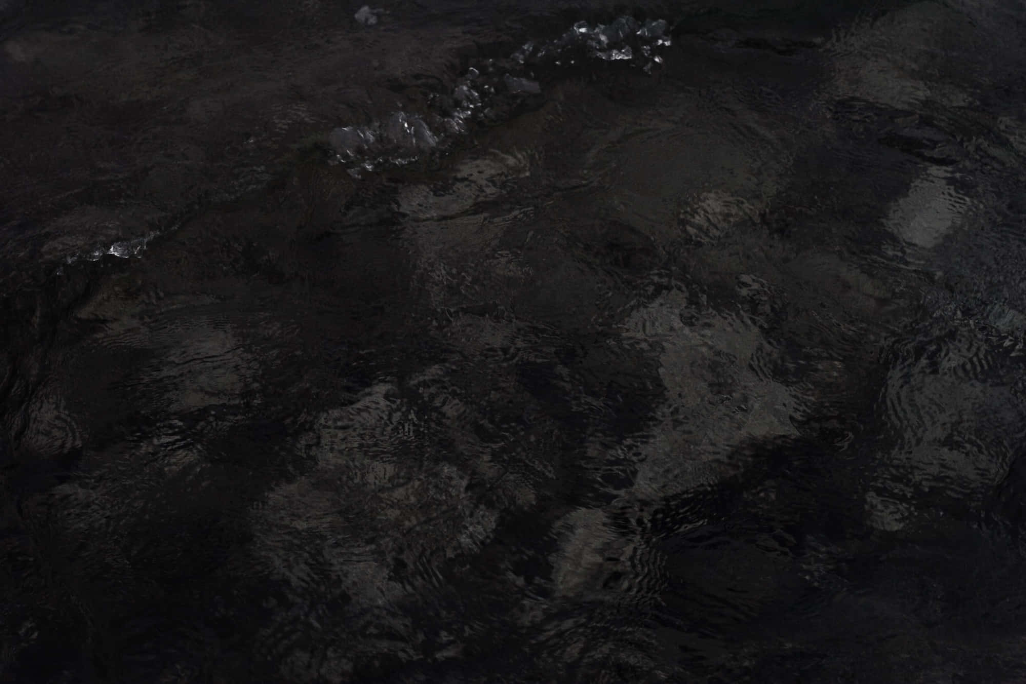 Dark Rock 桌布 壁紙 — 漆黑的水面泛起漣漪，帶有微妙的銀色亮點，在陰鬱的夜景中反射出微弱的光芒。