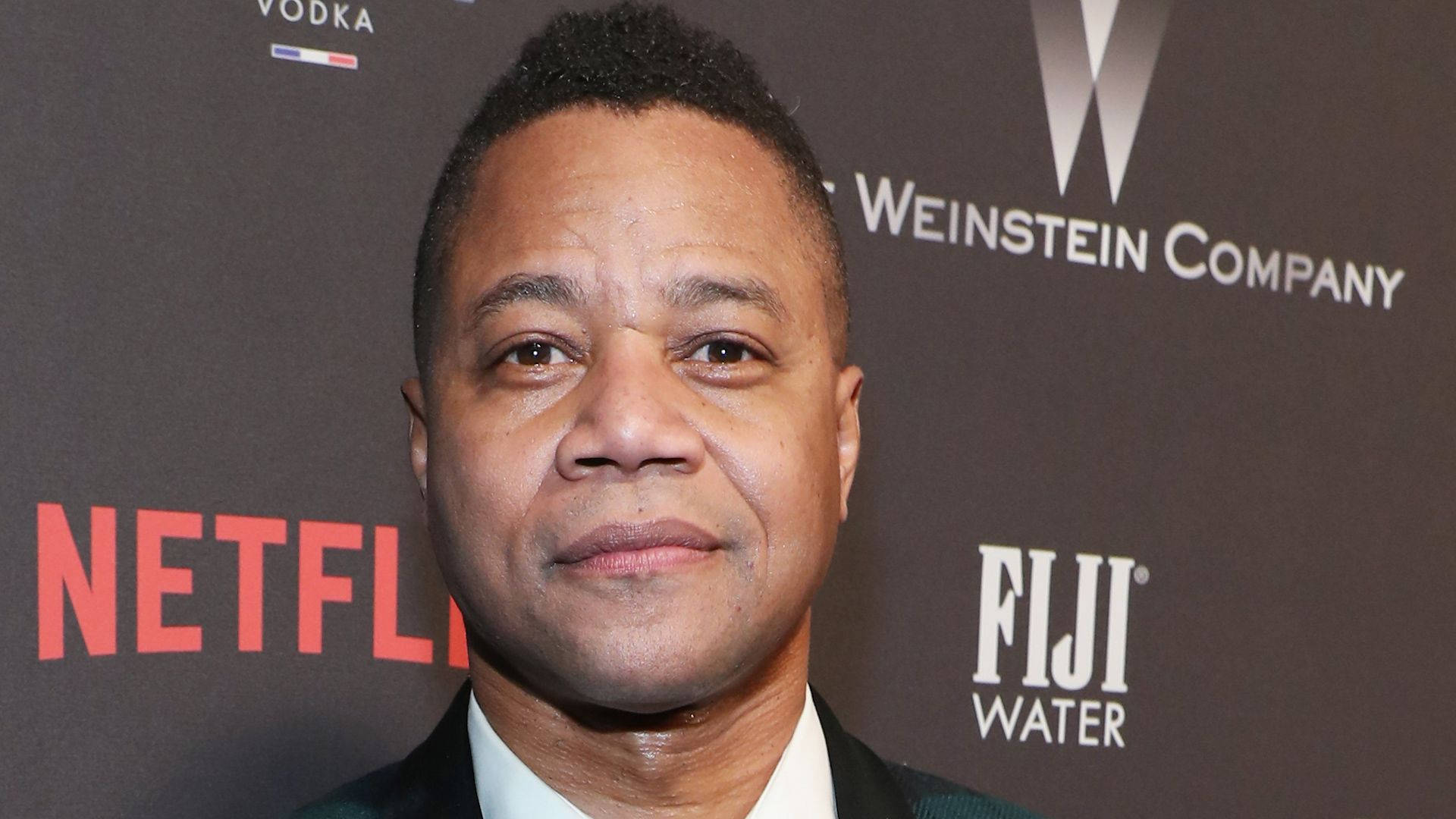 Netflix 桌布 壁紙 — 演員 Cuba Gooding Jr. 在紅地毯活動中對著鏡頭微笑，身後有 Netflix 和 Weinstein Company 的標誌。