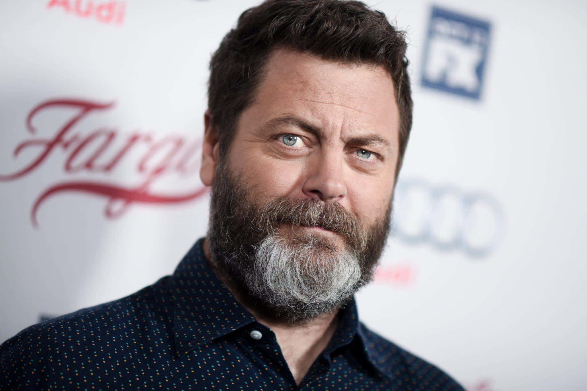 nick offerman 桌布 壁紙 — 演員 Nick Offerman 留著灰白鬍鬚，眼神專注，身後有 'Fargo' 和 'FX' 標誌的紅地毯活動。