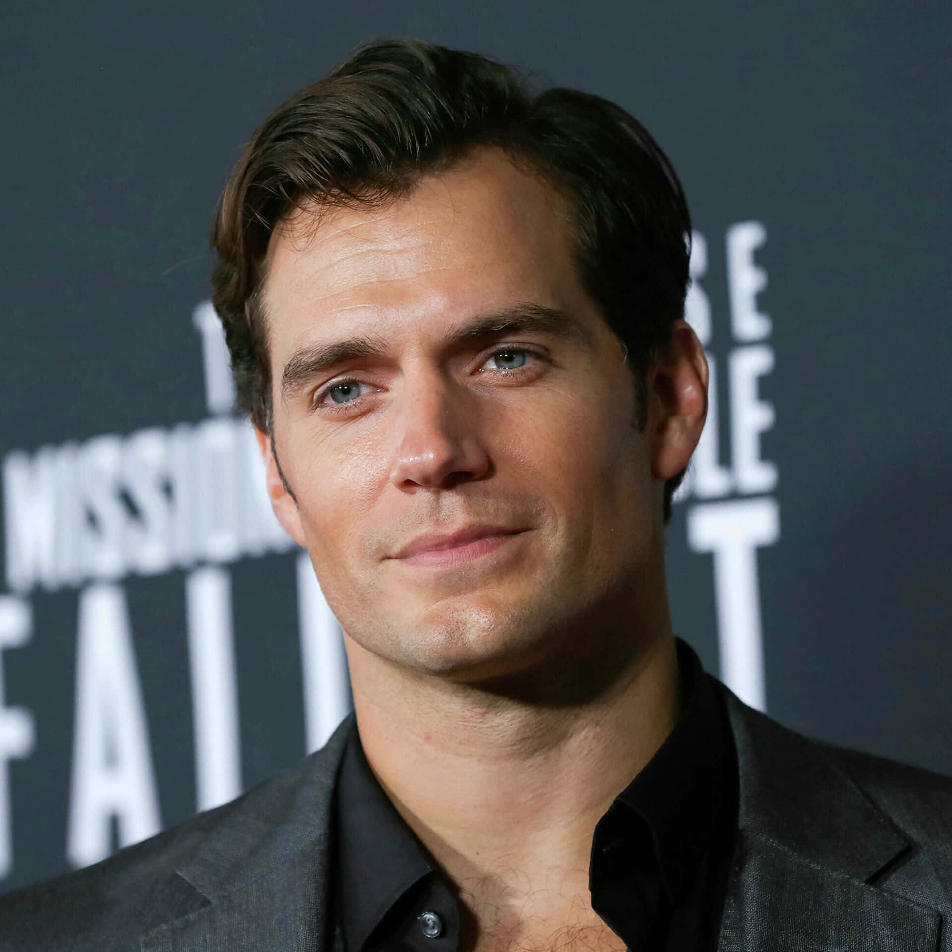Henry Cavill 桌布 壁紙 — 演員亨利卡維爾在電影首映會上的特寫肖像，背景為深色並帶有白色文字。