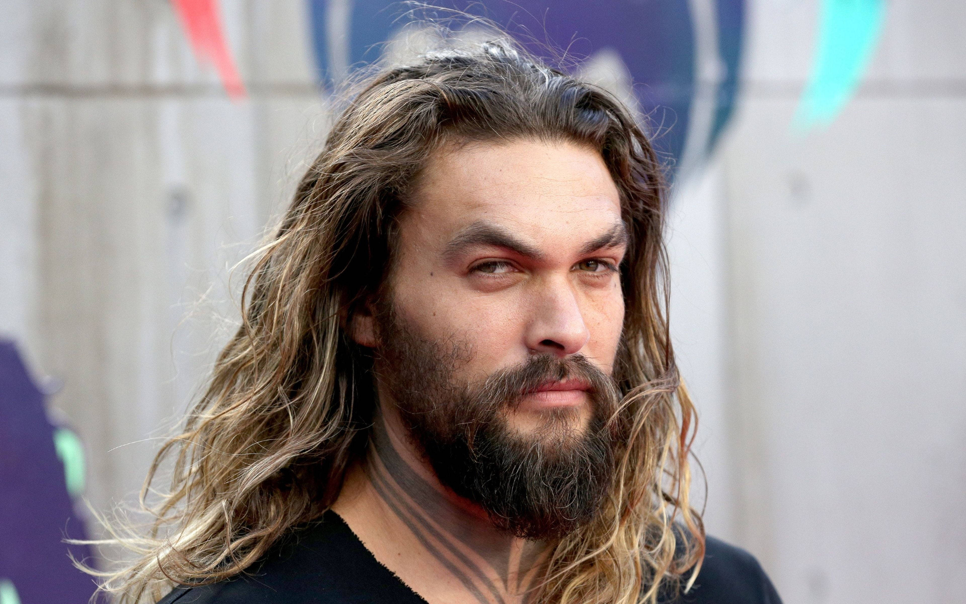 jason 桌布 壁紙 — 演員傑森摩莫亞（Jason Momoa）留著長捲髮和鬍鬚，專注地凝視著色彩繽紛的塗鴉牆。