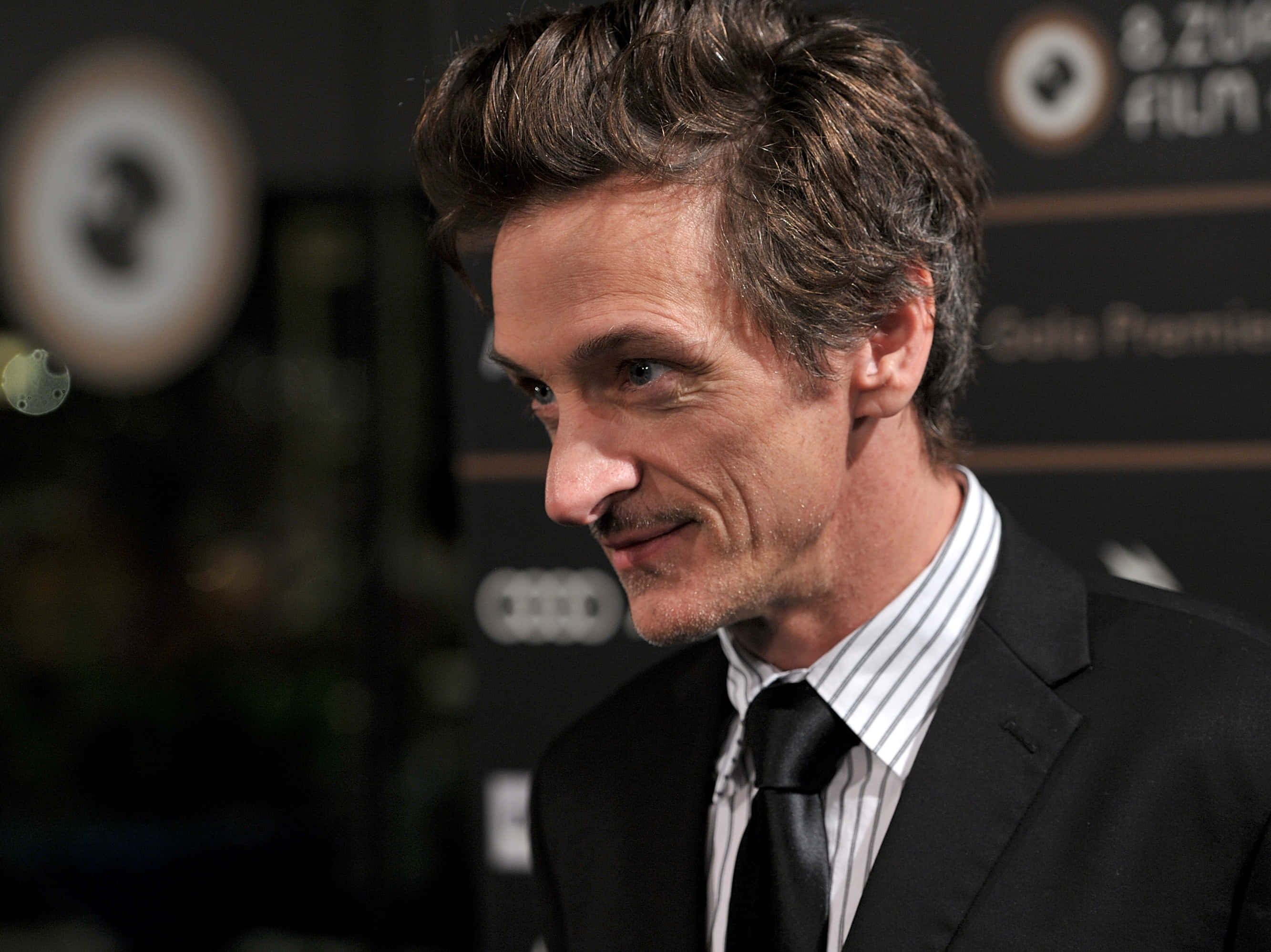 John Hawkes 桌布 壁紙 — 演員兼導演安德魯·加菲爾德在電影首映活動中穿著黑色西裝和條紋襯衫的特寫。
