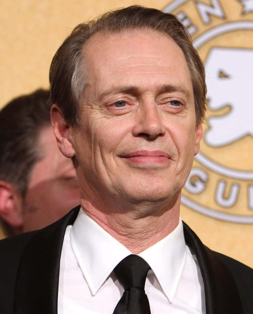 steve buscemi 桌布 壁紙 — 演員史提夫·布希米在金色背景的正式活動中穿著黑色燕尾服，露出微妙的微笑。