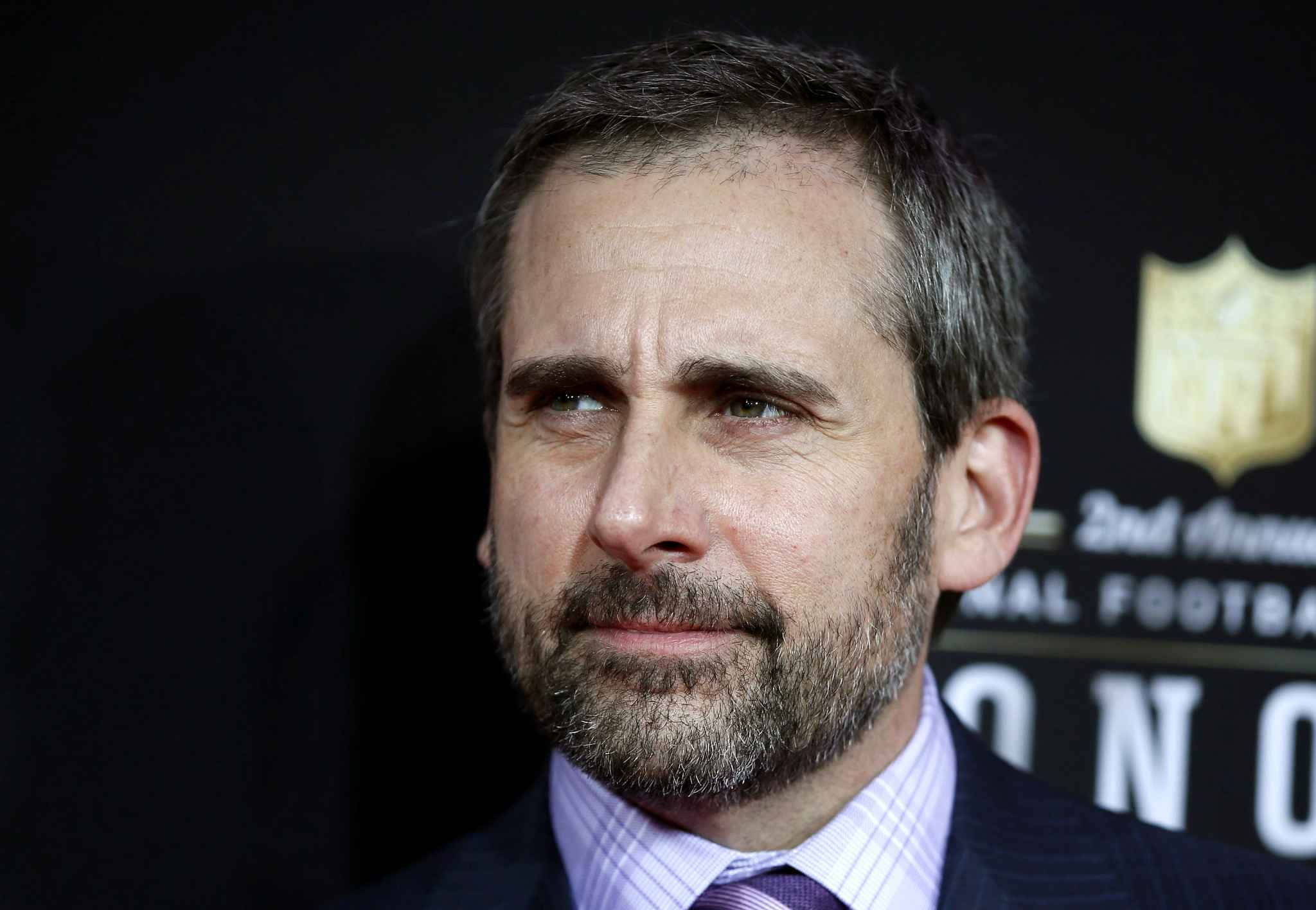 steve carell 桌布 壁紙 — 演員史提夫卡爾身穿西裝在NFL活動中嚴肅地望向鏡頭外的特寫肖像。