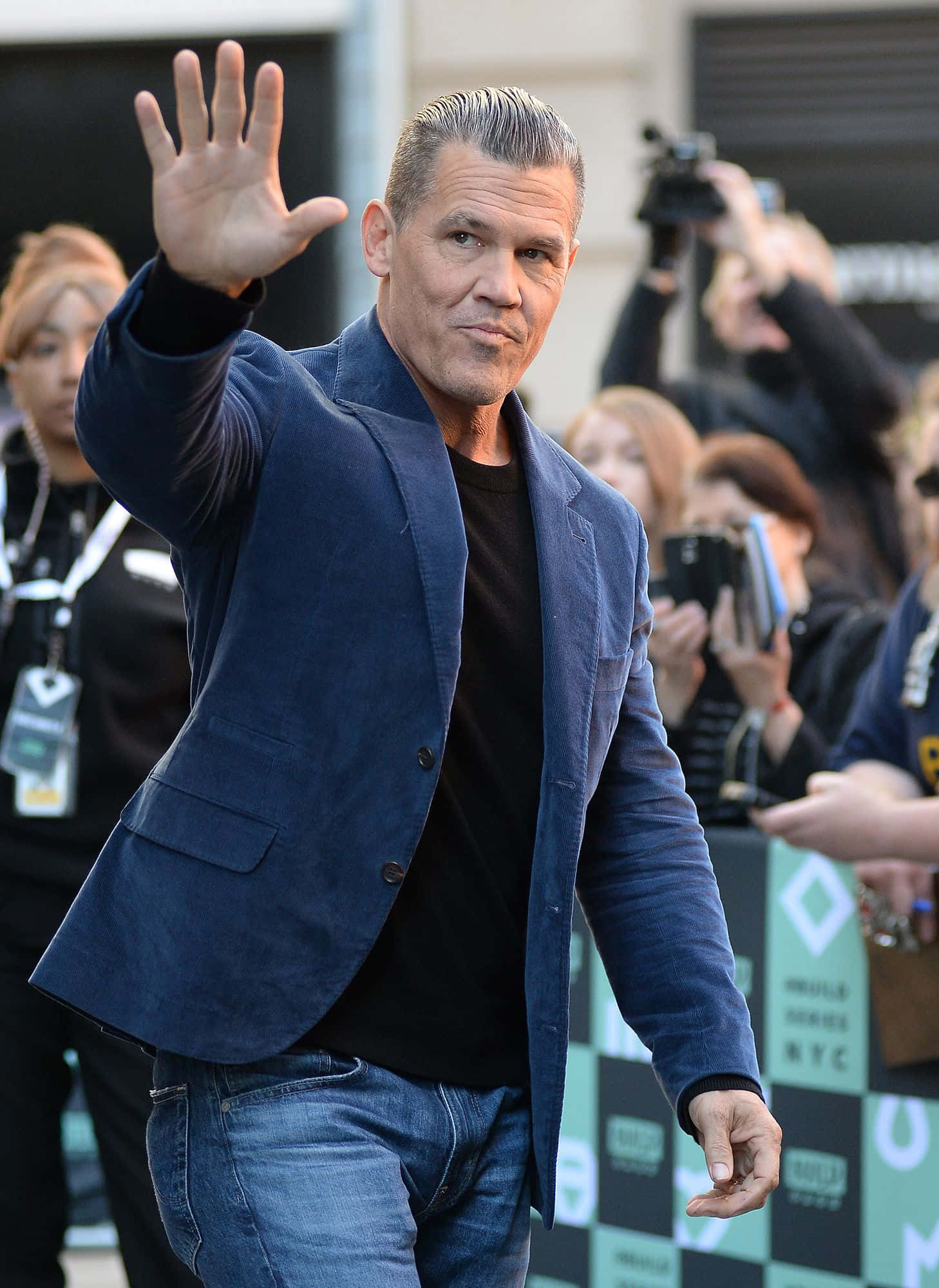 Josh Brolin 桌布 壁紙 — 演員喬許布洛林在公開活動中穿著藍色西裝外套和牛仔褲向粉絲揮手，背景有攝影師。