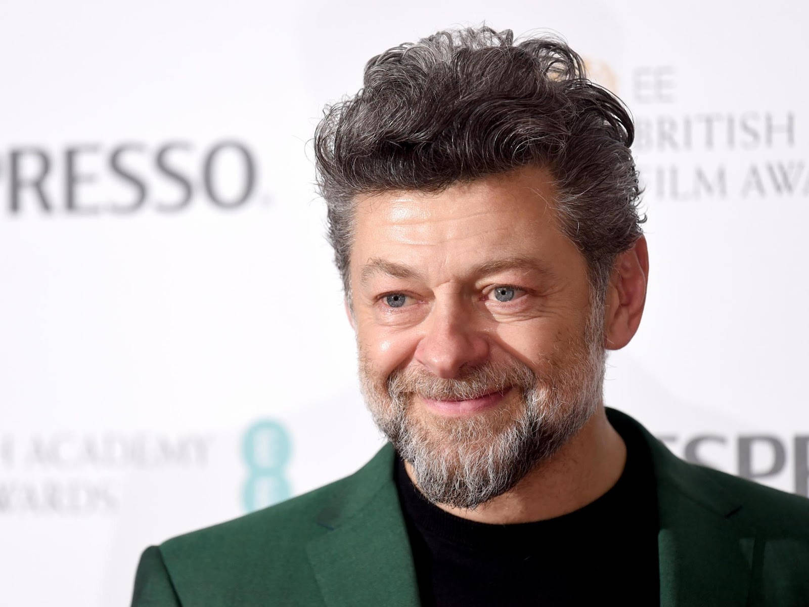 actor 桌布 壁紙 — 演員安迪·瑟克斯在EE英國電影學院獎紅地毯上穿著綠色西裝，溫暖地微笑。