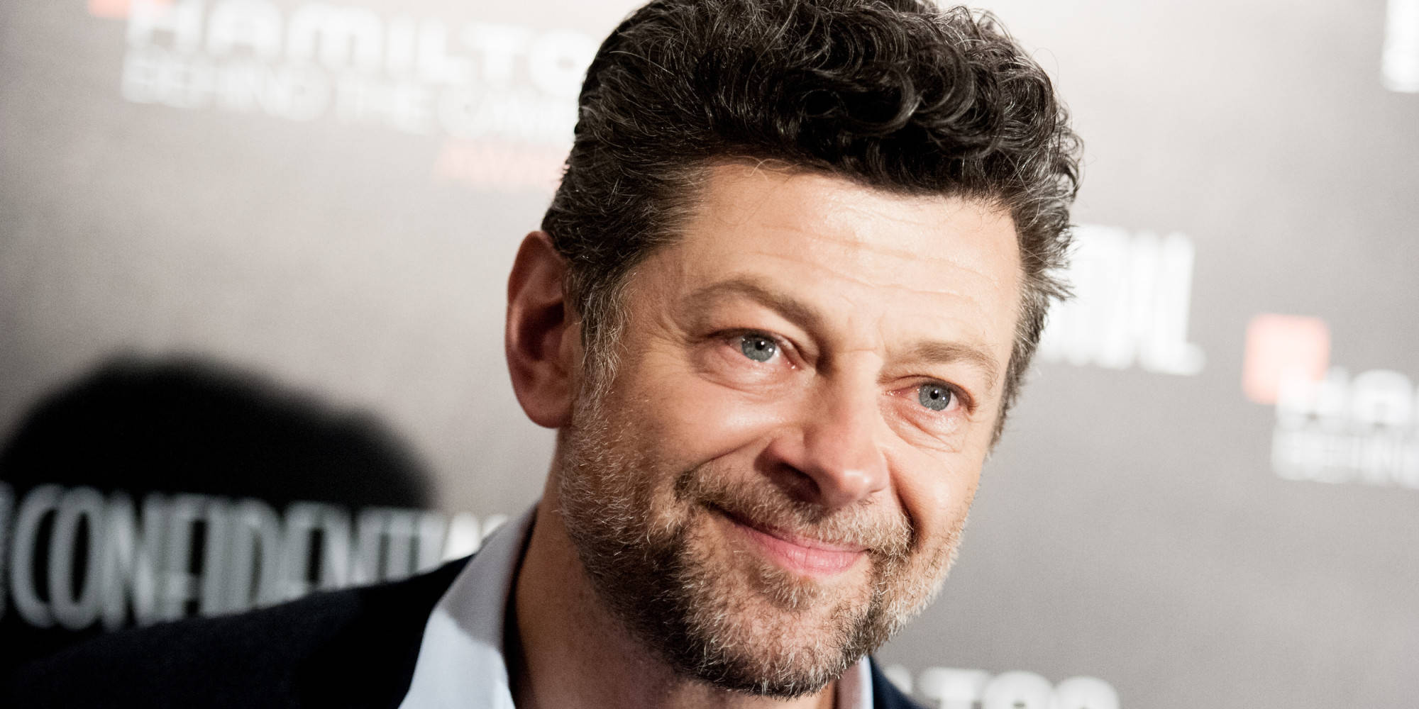 actor 桌布 壁紙 — 演員安迪·瑟克斯在品牌活動背景前對著鏡頭溫暖微笑。