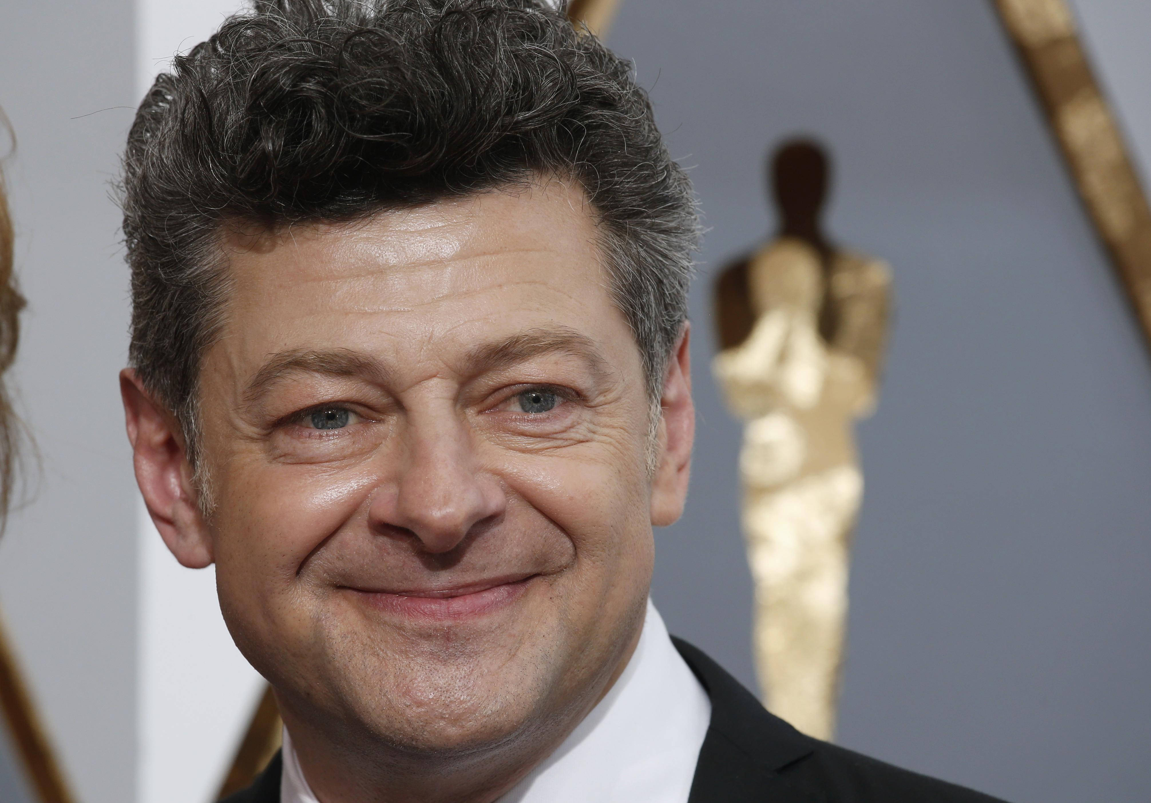 actor 桌布 壁紙 — 演員安迪·瑟克斯在紅地毯上對著鏡頭溫暖微笑，背景是金色奧斯卡獎座。