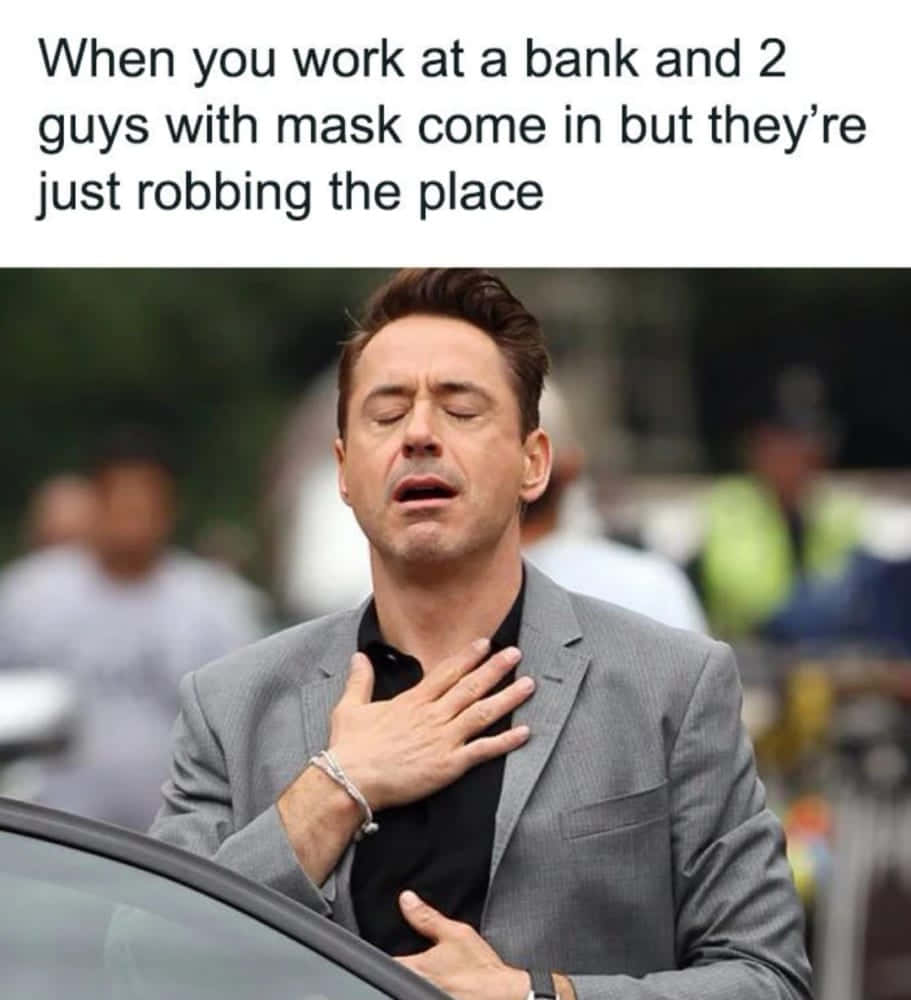 meme 桌布 壁紙 — 演員小勞勃·道尼（Robert Downey Jr.）閉上眼睛，手放在胸前，穿著灰色西裝，在戶外顯得惱怒。