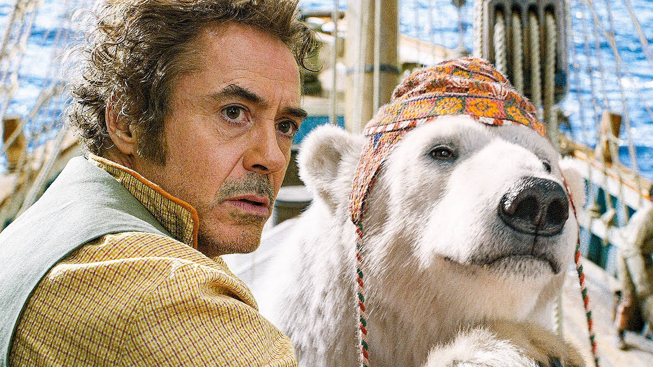 dolittle 桌布 壁紙 — 演員小勞勃·道尼（Robert Downey Jr.）和一隻戴著色彩繽紛圖案帽子的北極熊並肩站在船甲板上。