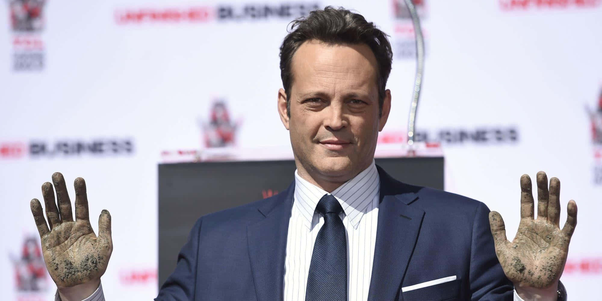 Vince Vaughn 桌布 壁紙 — 演員文斯·沃恩穿著筆挺西裝，在手印儀式中微笑展示沾滿泥濘的雙手。