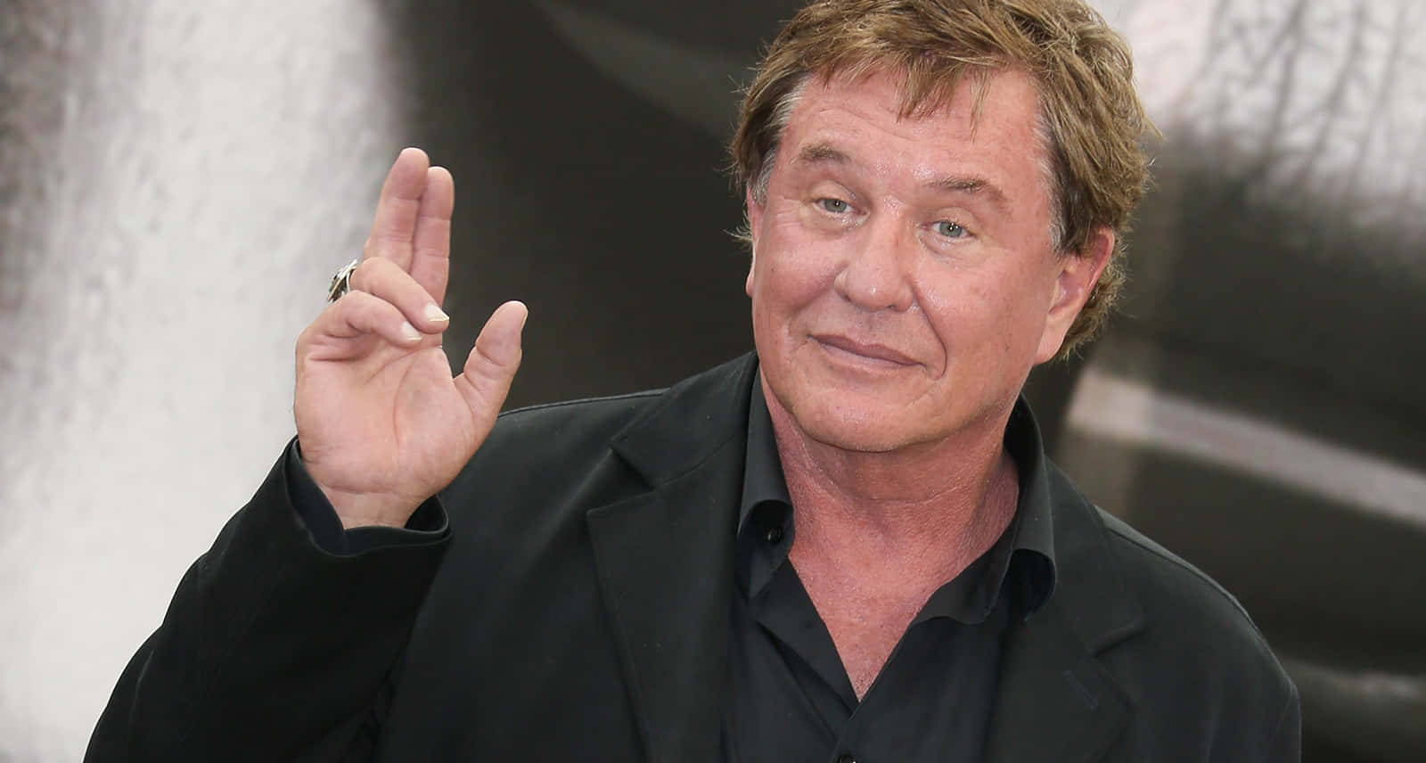 Tom Berenger 桌布 壁紙 — 演員方·基墨穿著黑色西裝和襯衫，比出和平手勢揮手。