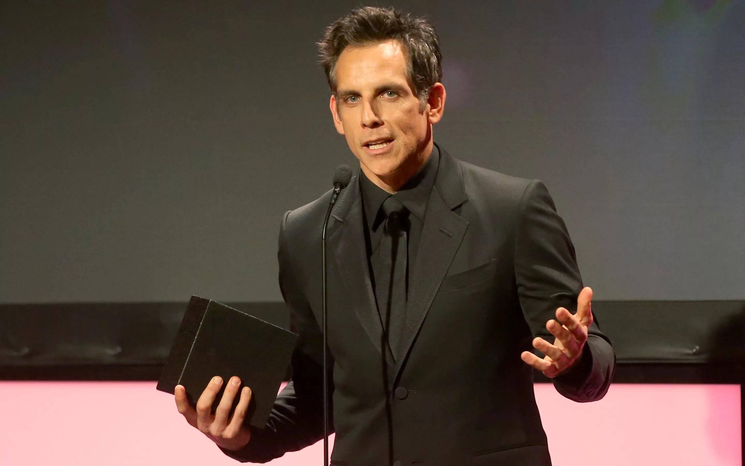 Ben Stiller 桌布 壁紙 — 演員班·史提勒身穿黑色西裝，在粉紅色燈光的舞台上手持獎盃發表頒獎演講。
