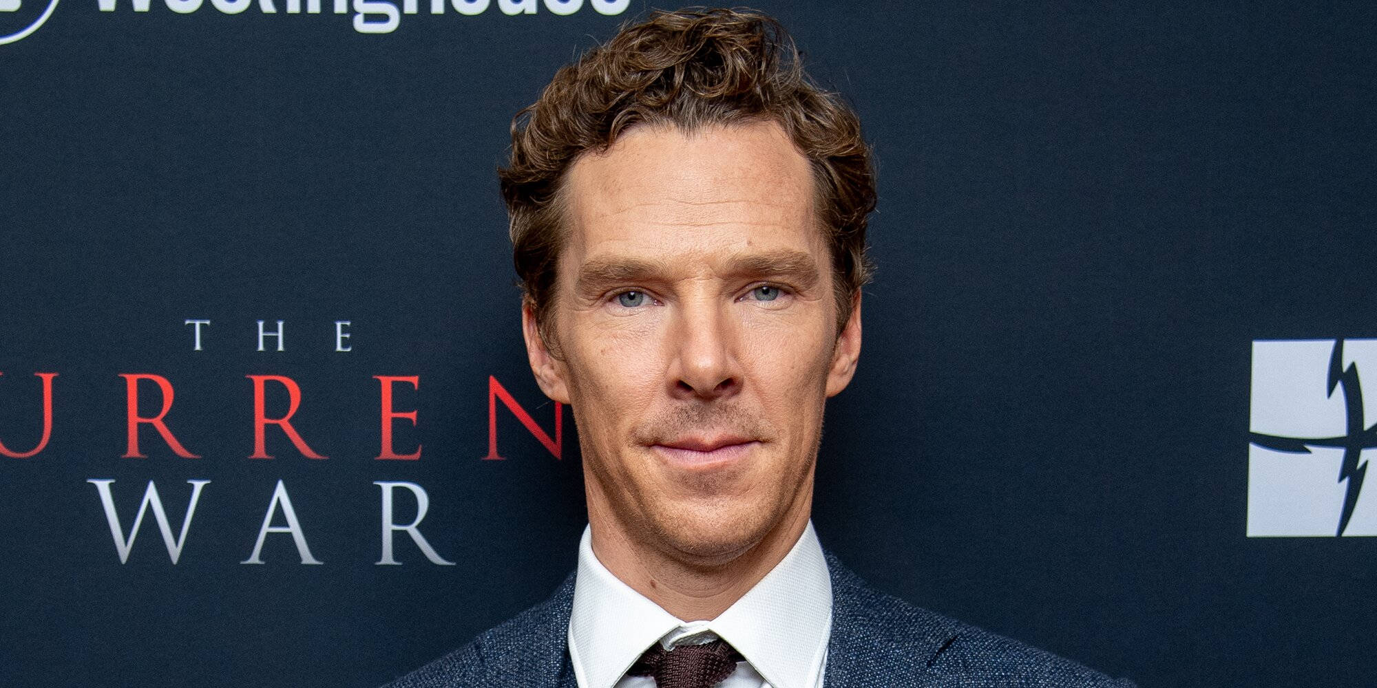 benedict 桌布 壁紙 — 演員班尼狄克·康柏拜區身穿俐落西裝，在《電流大戰》背景下自信地擺姿勢於電影首映禮。