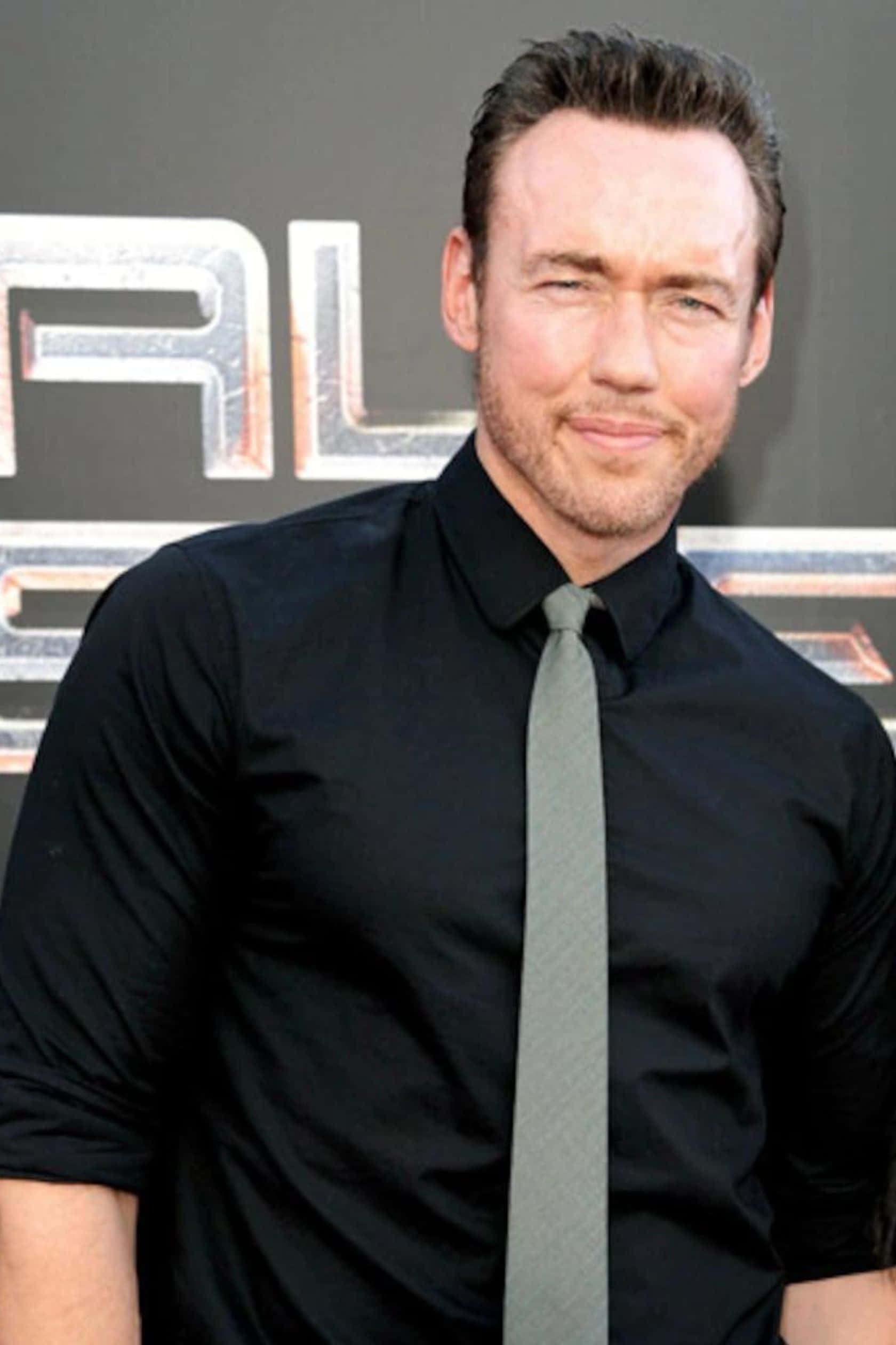 Kevin Durand 桌布 壁紙 — 演員理查德·阿米蒂奇在電影首映活動中穿著黑色襯衫和灰色領帶，自信地微笑。