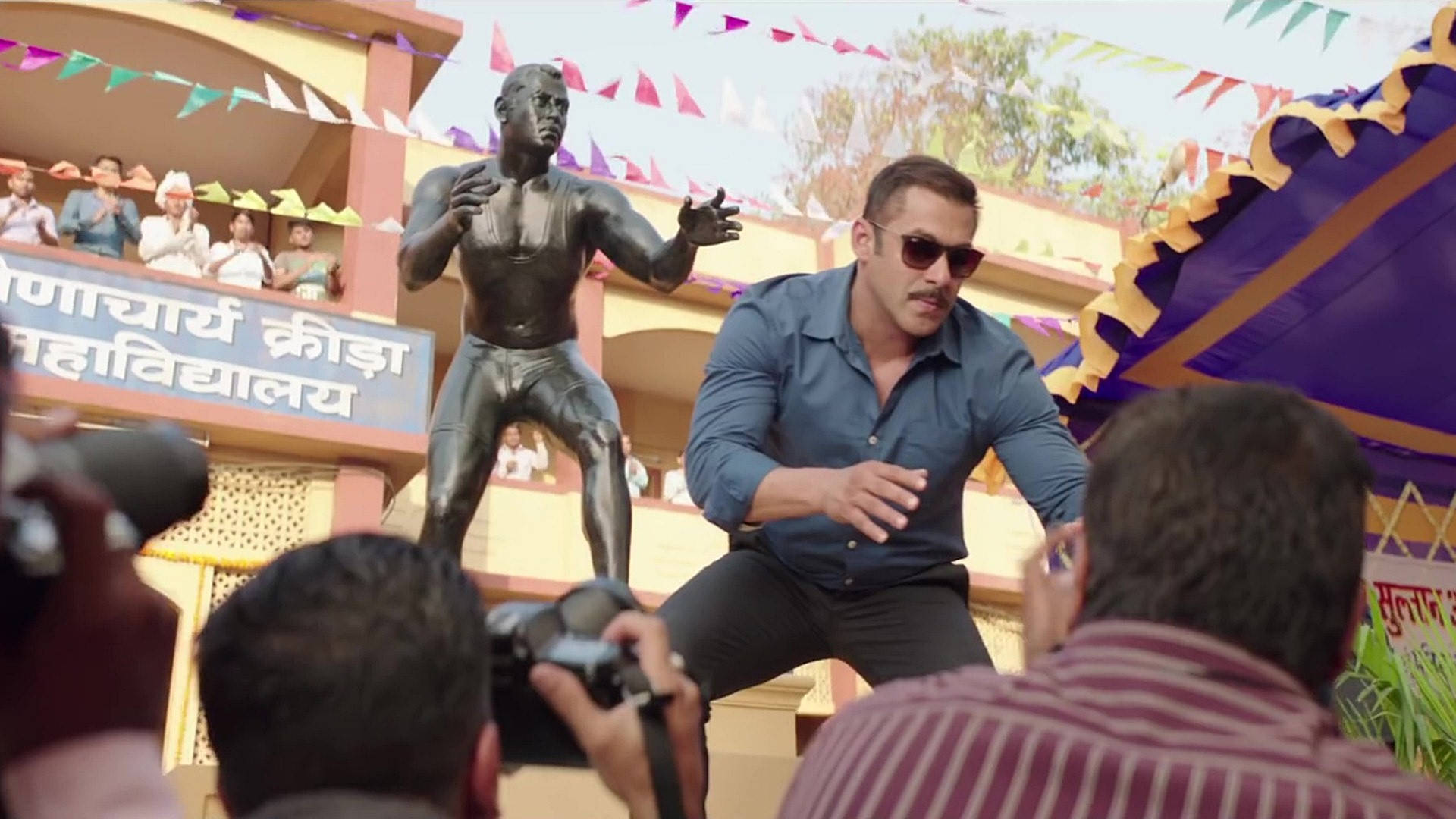 salman khan HD 桌布 壁紙 — 演員薩爾曼·汗在一個節日戶外活動中，動態地站在自己的銅像旁擺姿勢，攝影師捕捉這一刻。