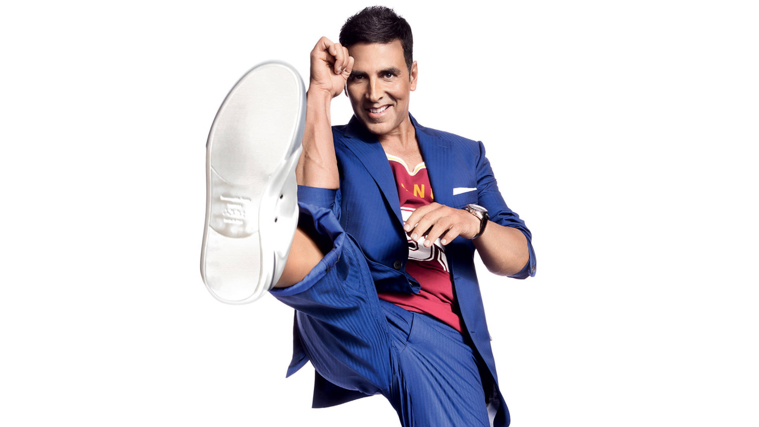 Akshay Kumar 桌布 壁紙 — 演員阿克謝·庫馬爾在純白背景下穿著藍色西裝和紅色襯衫擺出俏皮姿勢。