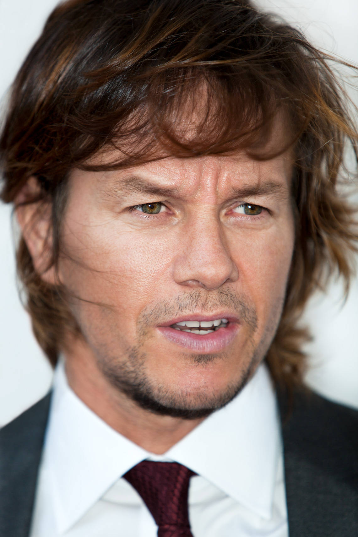 Mark Wahlberg 桌布 壁紙 — 演員馬克·華伯格的特寫肖像，凌亂的棕色頭髮和銳利的目光，身穿深色西裝和栗色領帶。