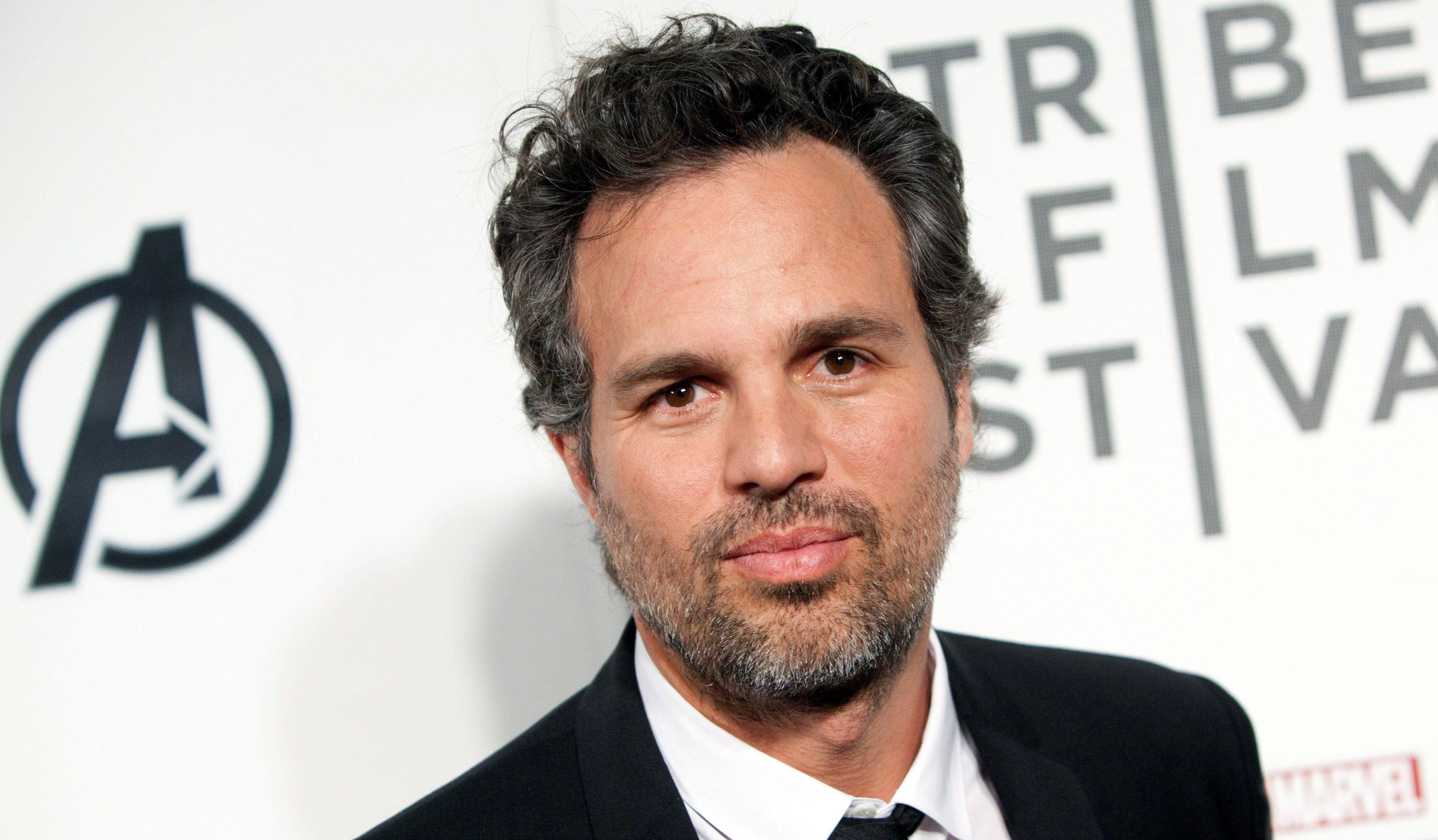 Mark Ruffalo 桌布 壁紙 — 演員馬克·魯法洛在紅毯活動中擺姿勢，背景為復仇者聯盟標誌和Marvel品牌。