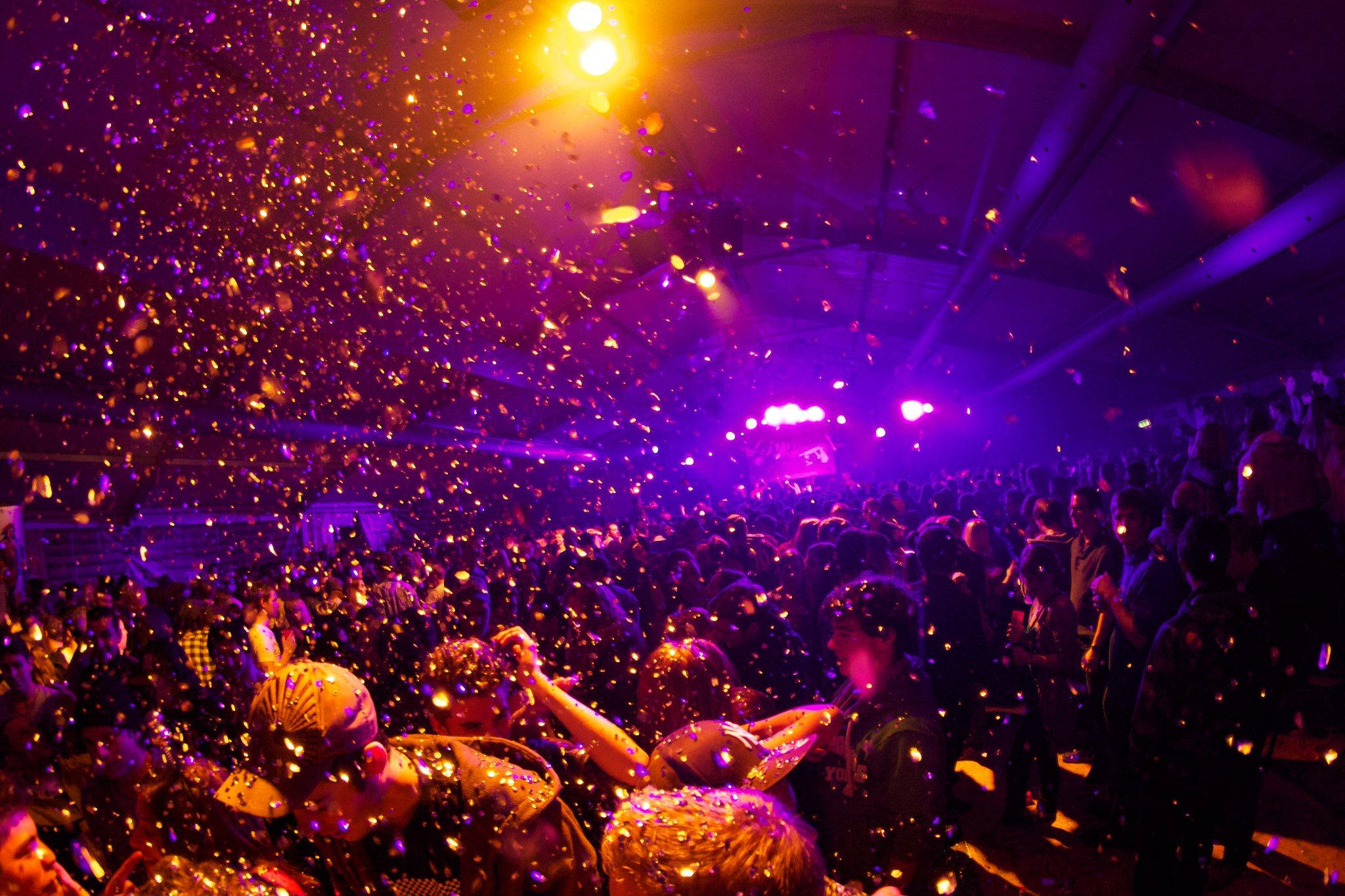 Party 桌布 壁紙 — 演唱會的人群在紫色燈光下跳舞，金色紙屑如雨般落下，營造出充滿活力的電子氛圍。