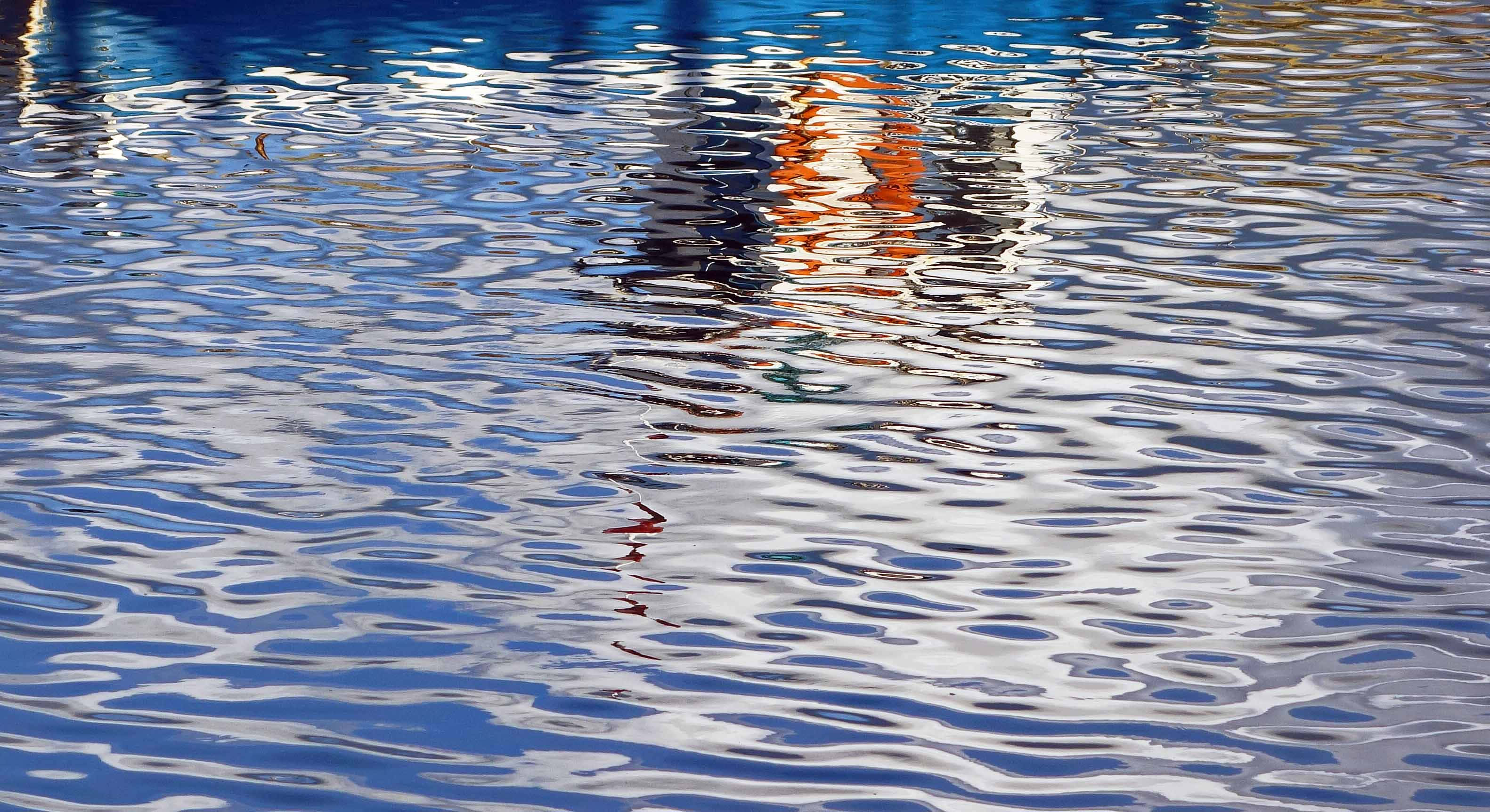 reflection 桌布 壁紙 — 漣漪扭曲了色彩繽紛建築物在閃爍藍色水面上的倒影。