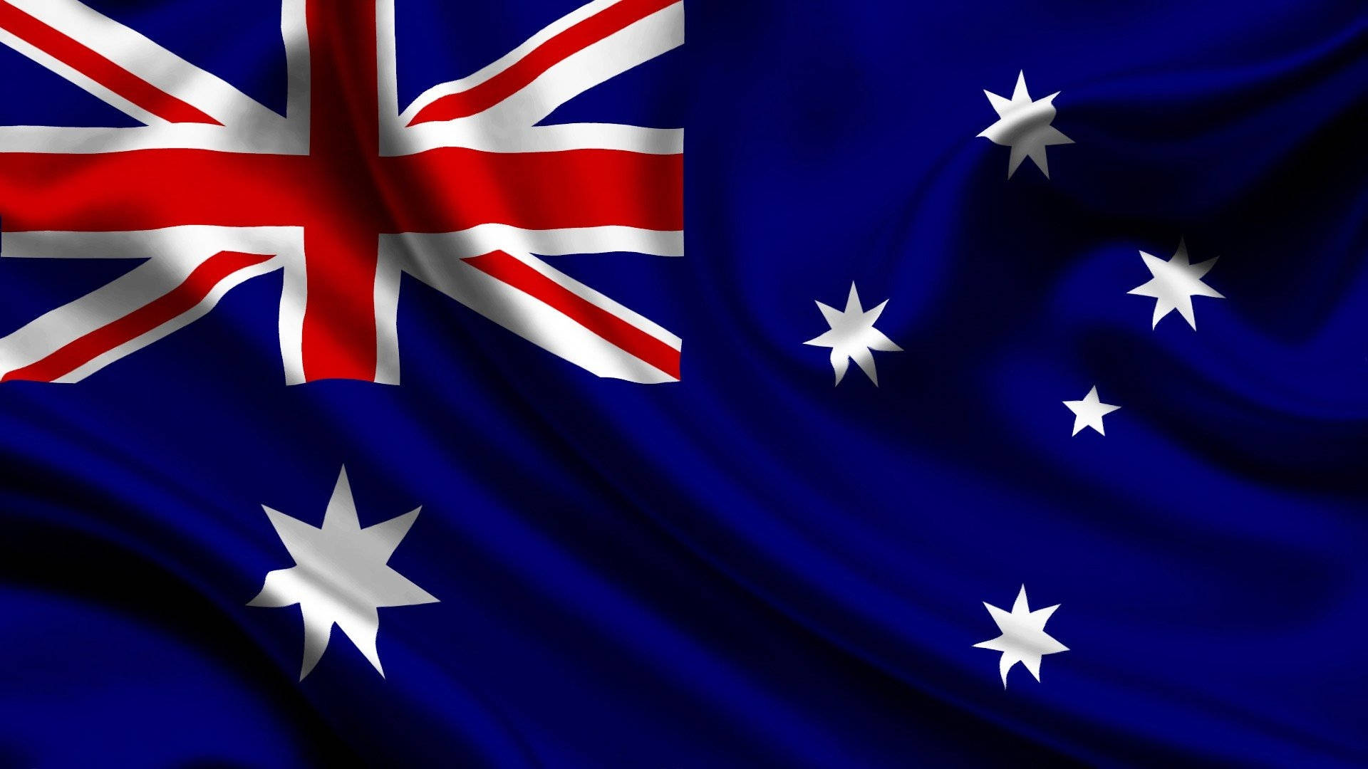 Flag 桌布 壁紙 — 澳洲國旗在深藍色布料上動態飄揚，帶有紅白相間的英國國旗和銀色星星，背景是黑暗的天空。