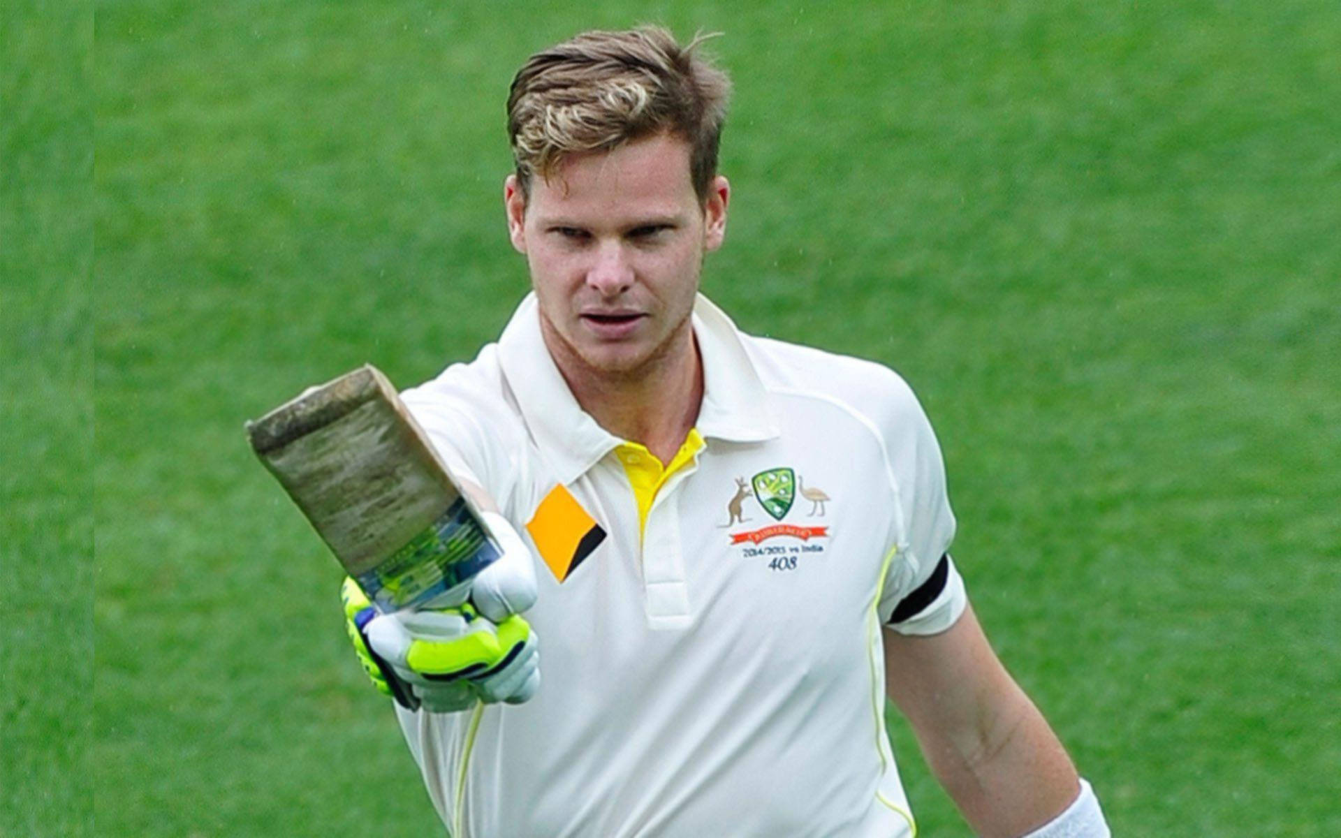 Steve Smith 桌布 壁紙 — 澳洲板球運動員手持磨損的球棒，神情專注地走過綠色球場。