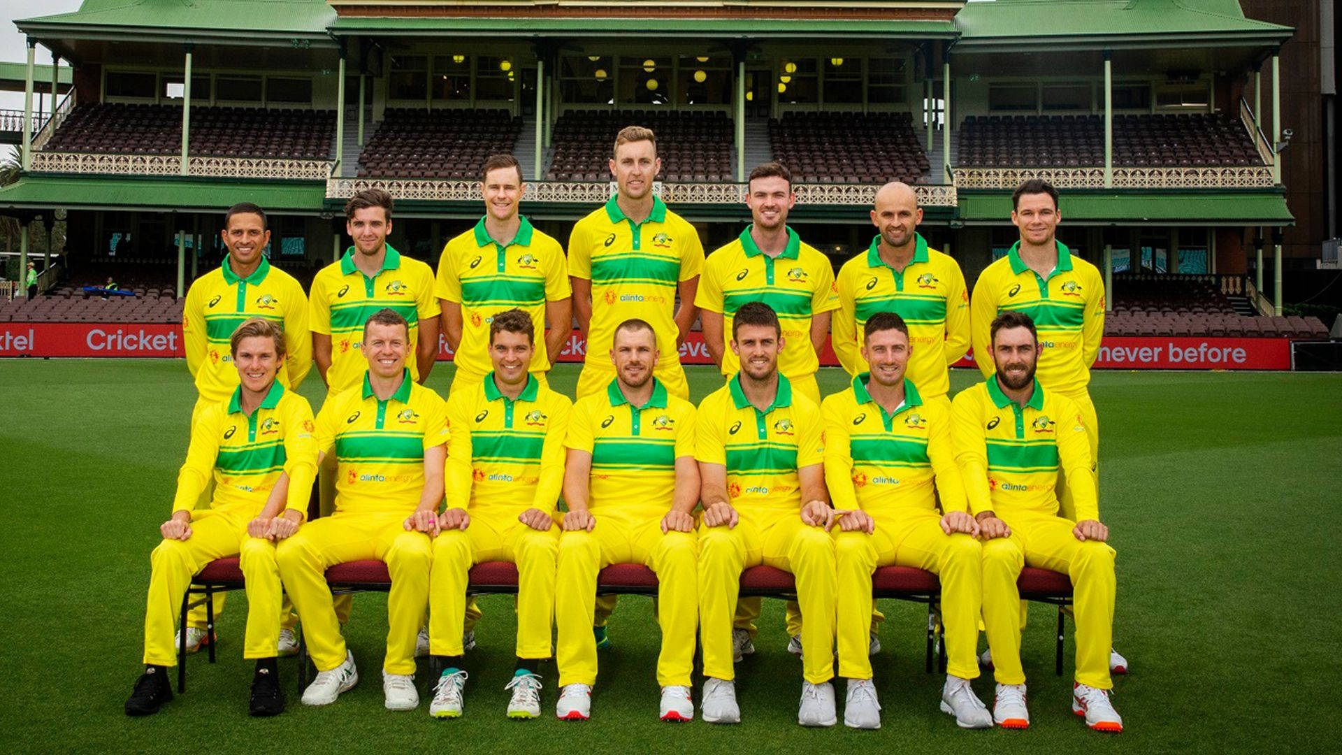australia cricket 桌布 壁紙 — 澳洲板球隊穿著鮮黃色和綠色制服，在宏偉體育館前的翠綠草地上正式擺姿勢。