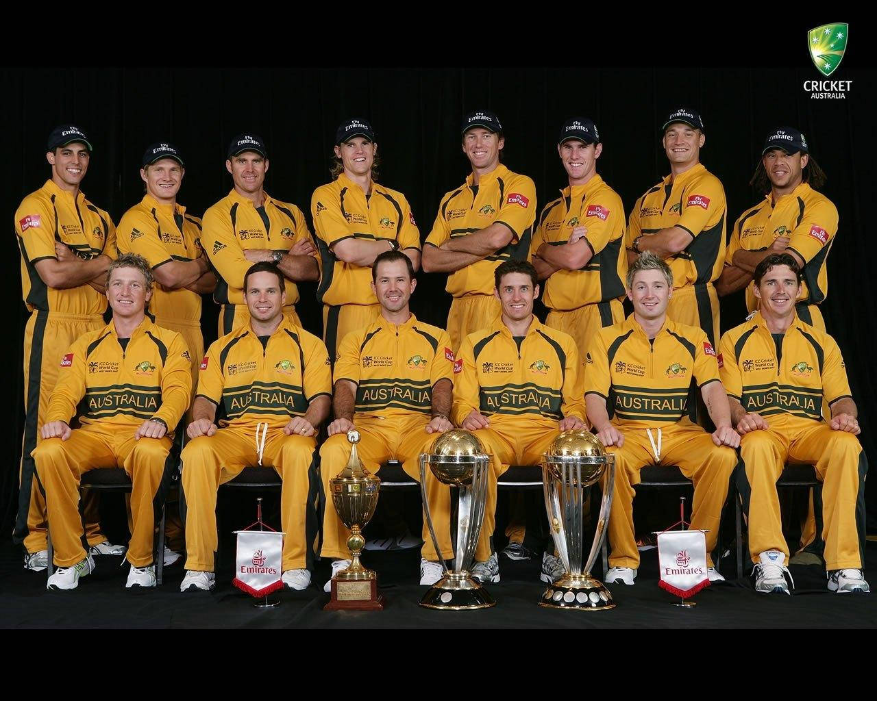 australia cricket 桌布 壁紙 — 澳洲板球隊身穿黃色制服，在黑色背景下與獎盃合影。