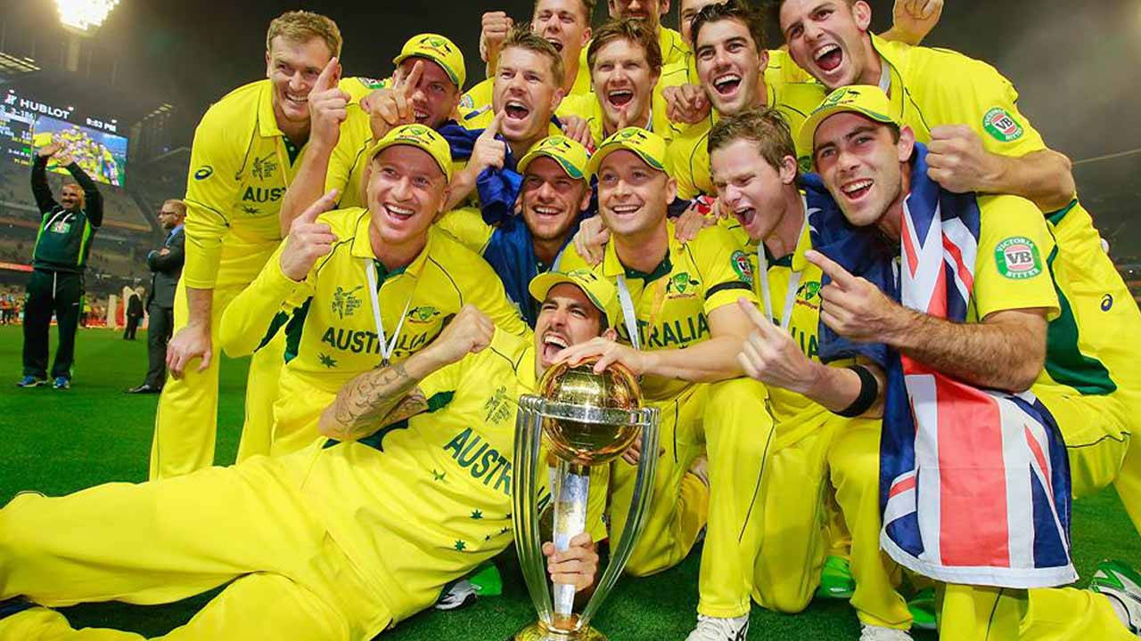 australia cricket 桌布 壁紙 — 澳洲板球隊身穿黃色球衣，在球場燈光下的綠色草地上歡欣鼓舞地慶祝，手持金色獎盃。