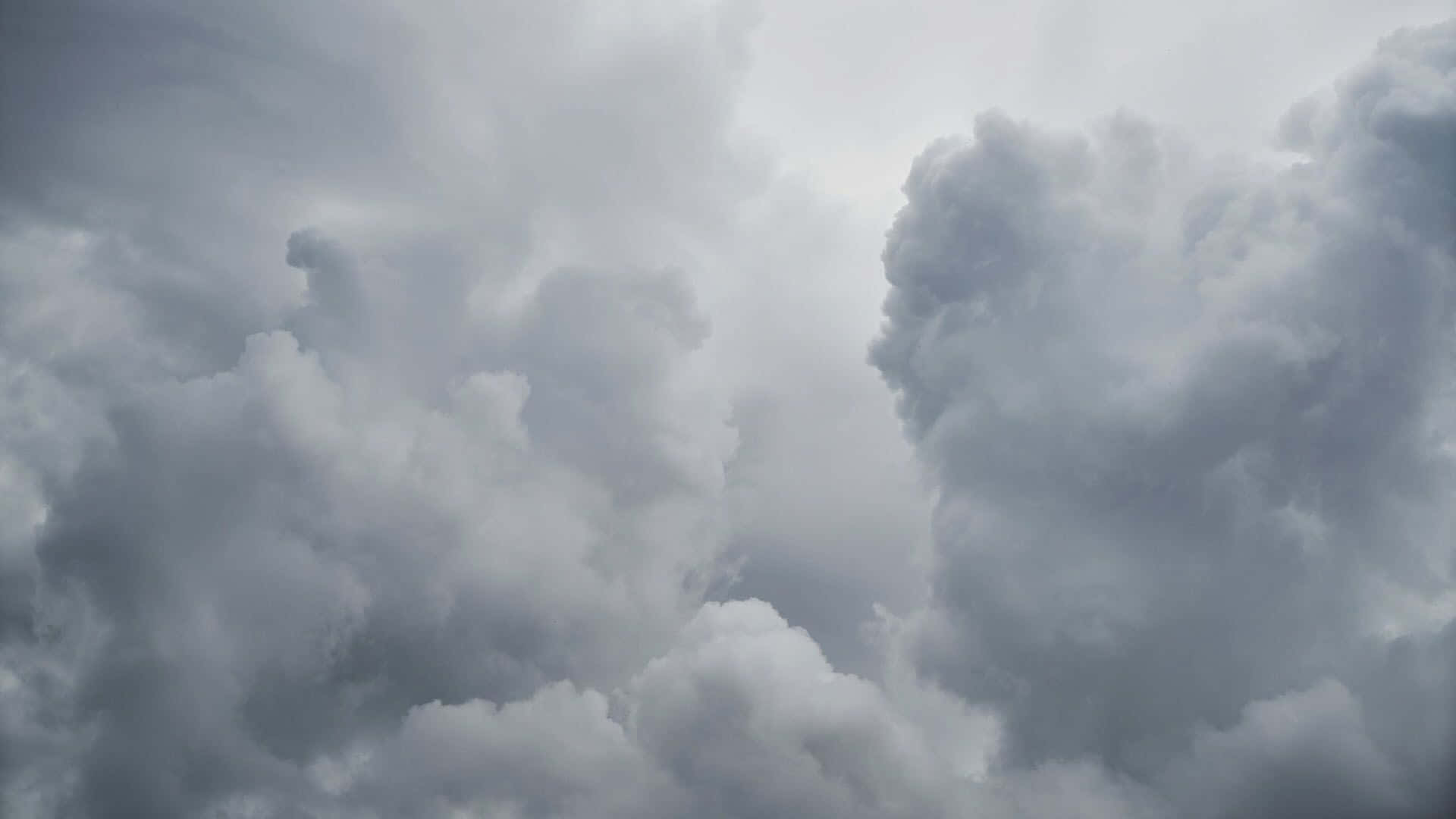 Weather 桌布 壁紙 — 濃密的灰色雲層在暴風雨前的戲劇性天空中旋轉，帶有柔和的白色高光。