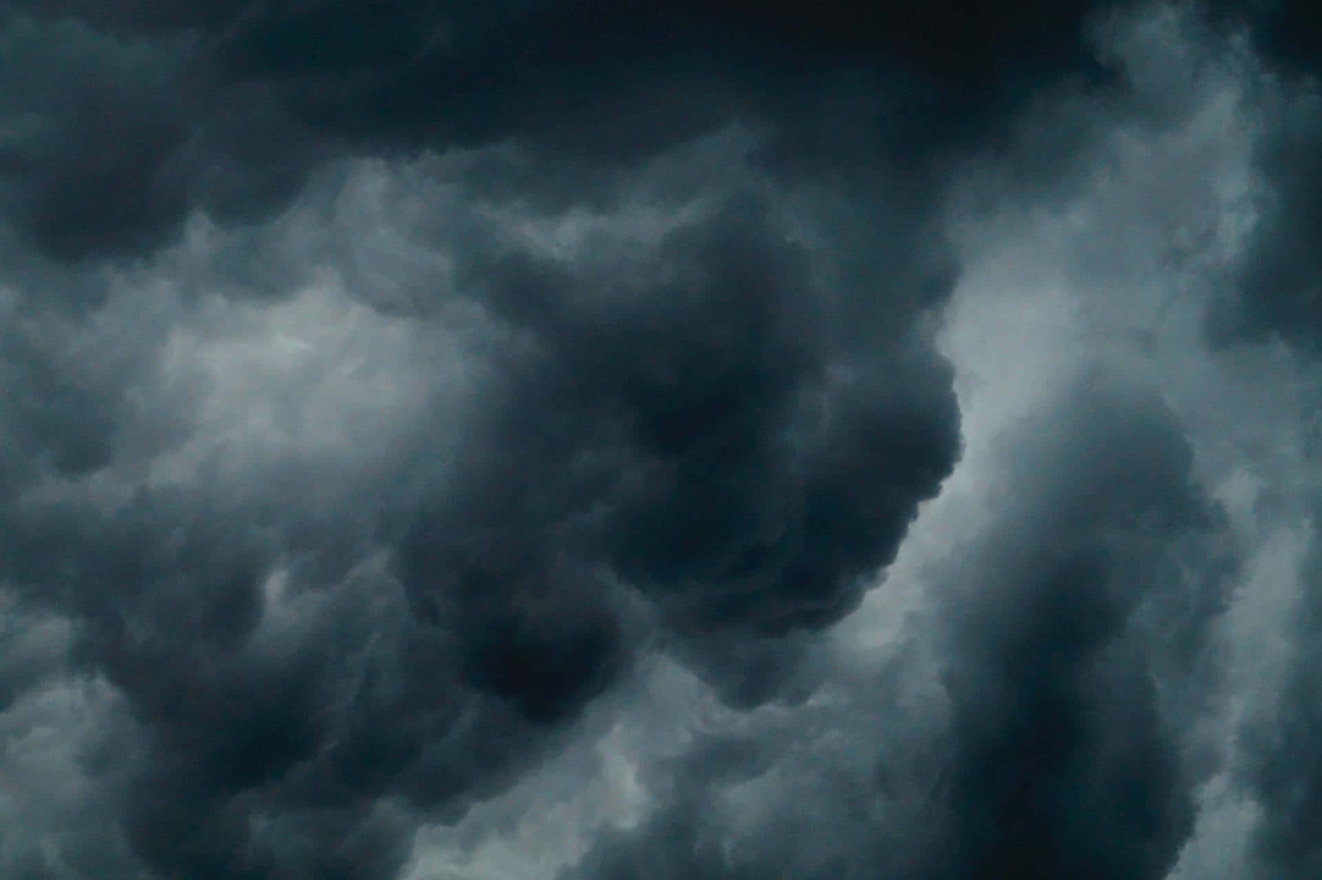 Stormy 桌布 壁紙 — 濃密的黑暗風暴雲在陰沉天空中翻騰，帶有陰暗的灰色和黑色色調。