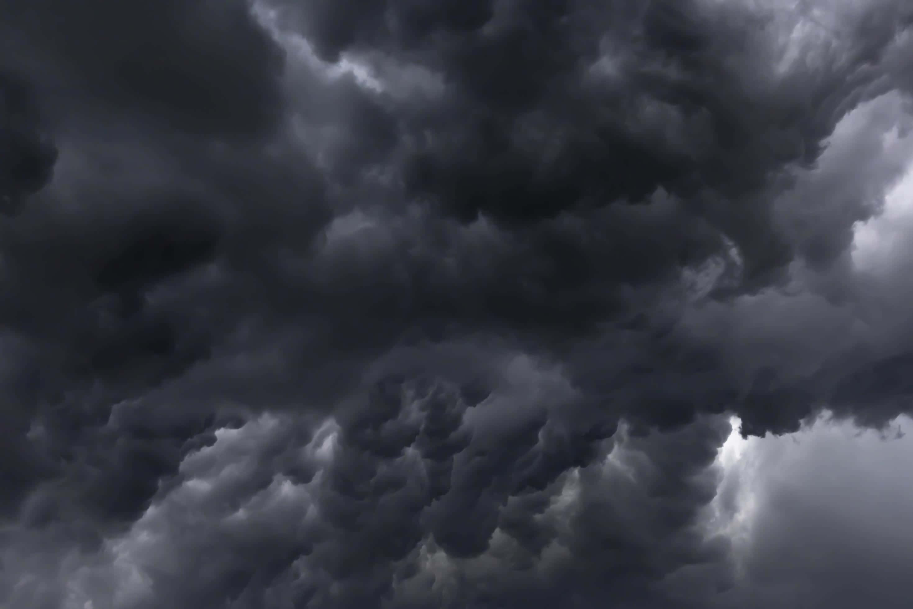 Dark Storm 桌布 壁紙 — 濃密的黑暗風暴雲層帶著戲劇性的紋理和不祥的灰色色調，在醞釀中的雷暴之前籠罩著。