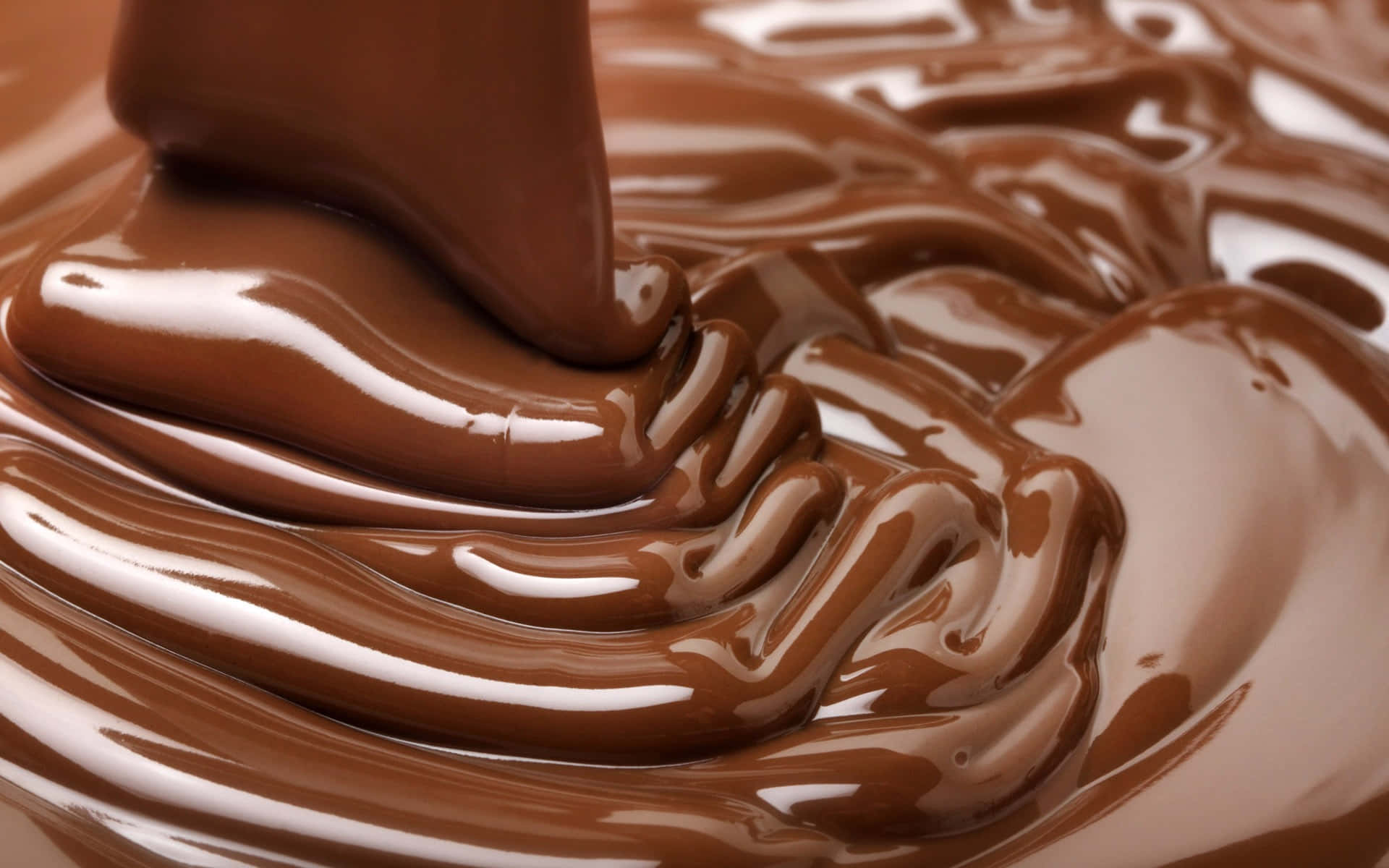 Dark Chocolate 桌布 壁紙 — 濃郁光澤的巧克力以厚絲帶狀流動，形成帶有明亮高光的漩渦圖案。