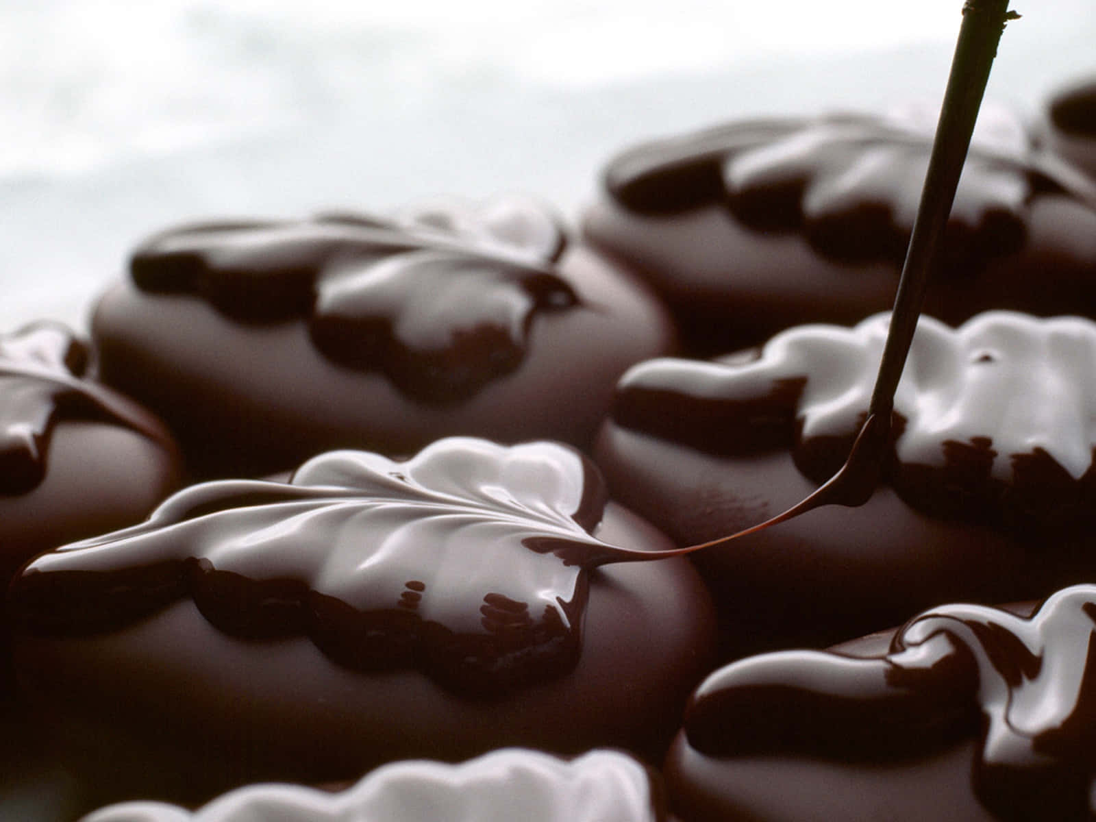 Chocolate 桌布 壁紙 — 濃郁光澤的巧克力滴落在圓形零食上，勺子舀起頹廢的漩渦。