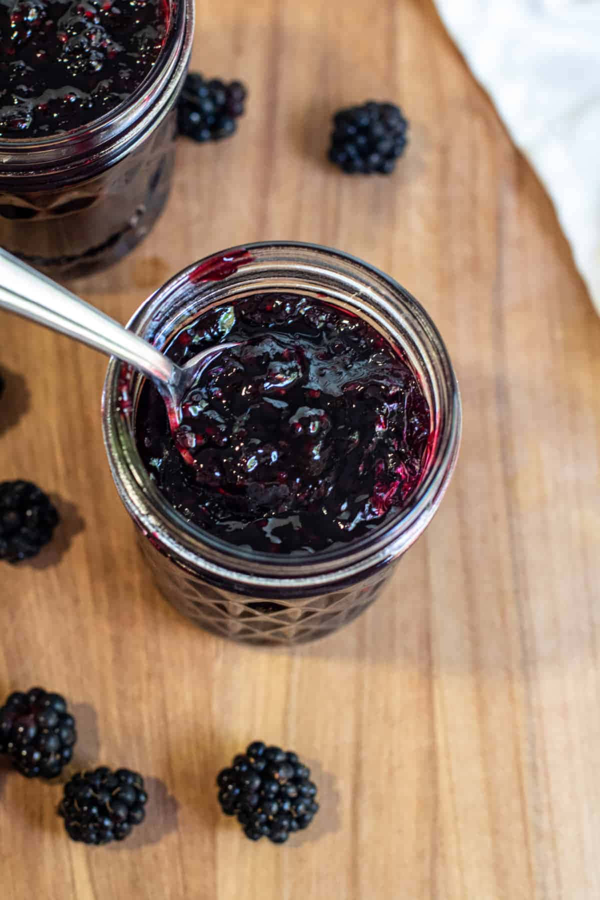 Blackberry Jam 桌布 壁紙 — 濃郁光澤的黑莓果醬玻璃罐，新鮮莓果散落在溫暖的木板上。