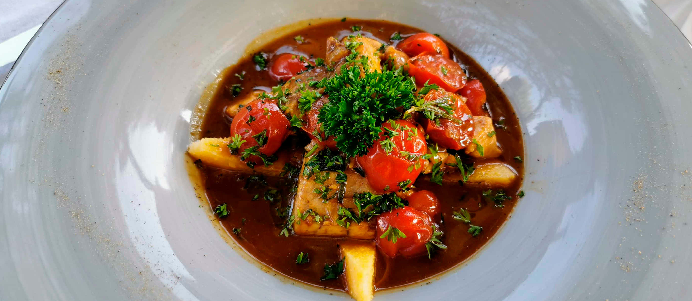 Croatia 桌布 壁紙 — 濃郁燉菜，搭配嫩肉、櫻桃番茄和新鮮歐芹，盛載於淺灰色碗中。